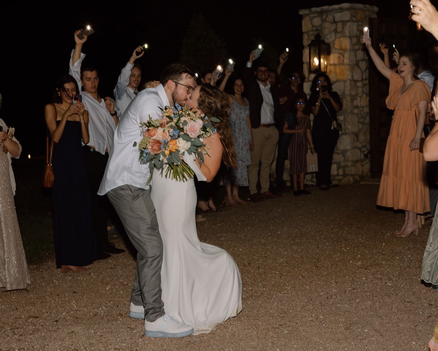 Newlyweds share a celebratory moment surrounded by sparkler-holding guests.