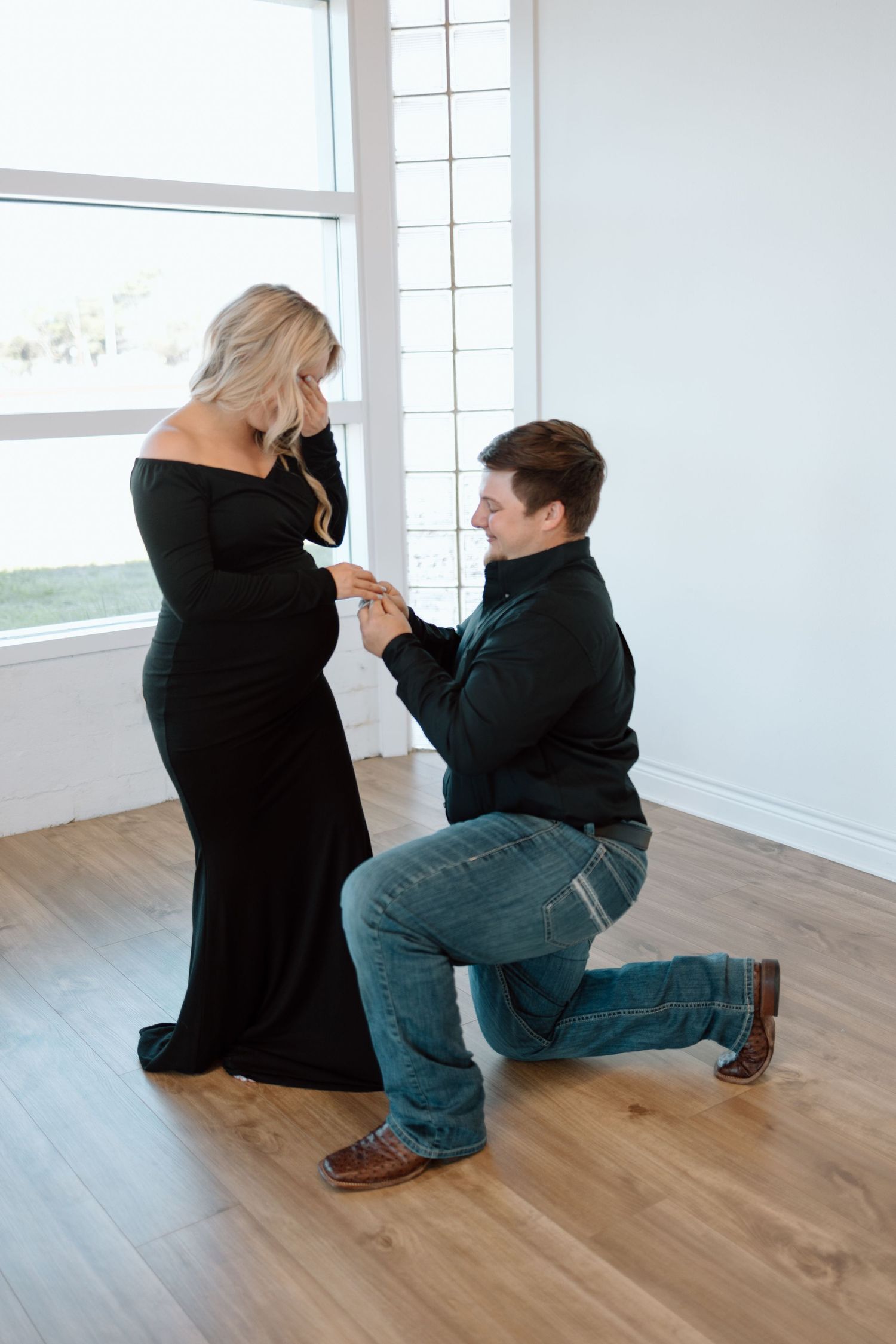 Marriage proposal scene with a couple in a minimalist room with hardwood floors and bright windows.