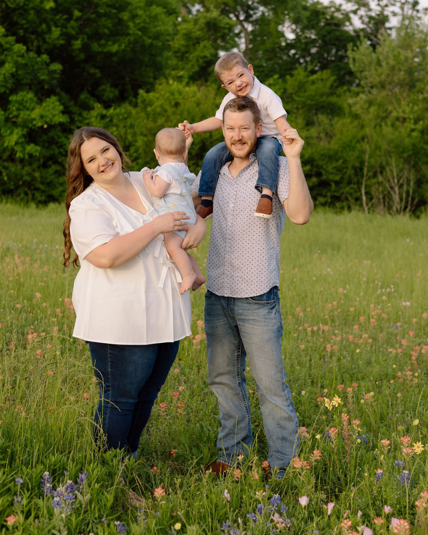 A family stands together in a wildflower meadow during golden hour in summer.
