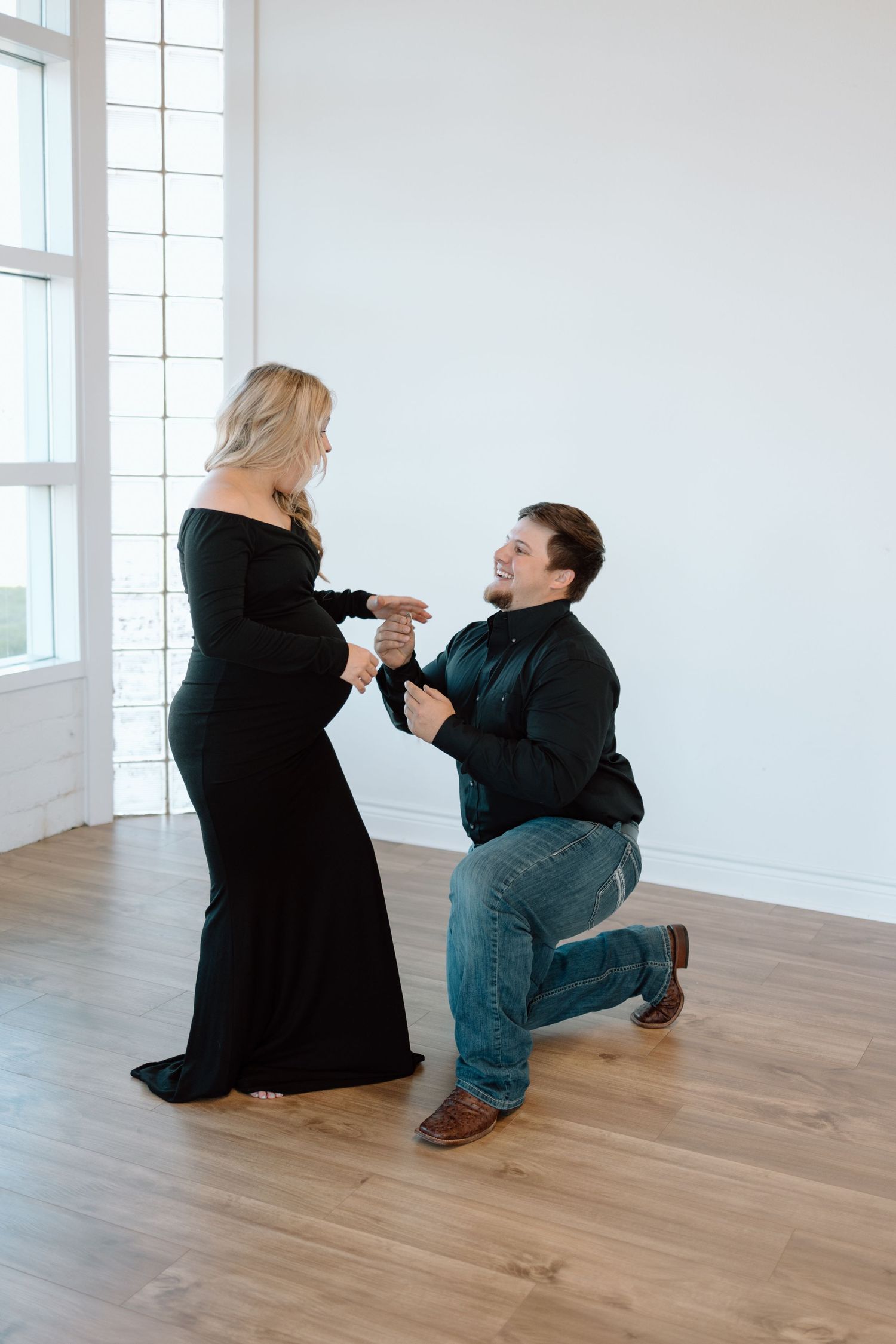 A romantic moment unfolds in a bright minimalist room with wooden flooring as someone kneels during a proposal.