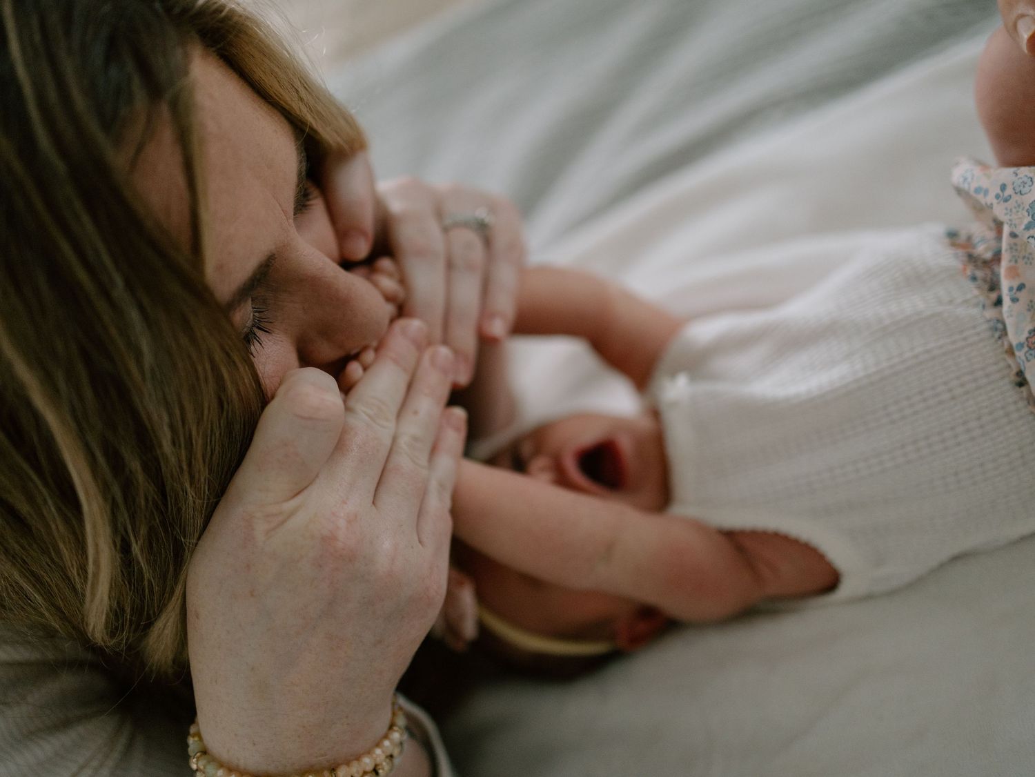 Someone rests peacefully on white bedding with hands held close to their face in a serene sleeping pose.