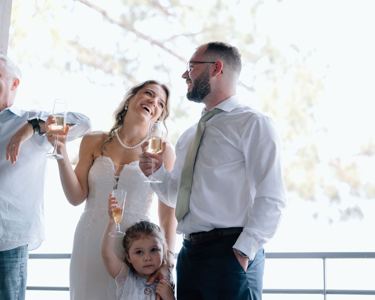 A joyful celebration moment at a wedding reception with guests raising champagne glasses.