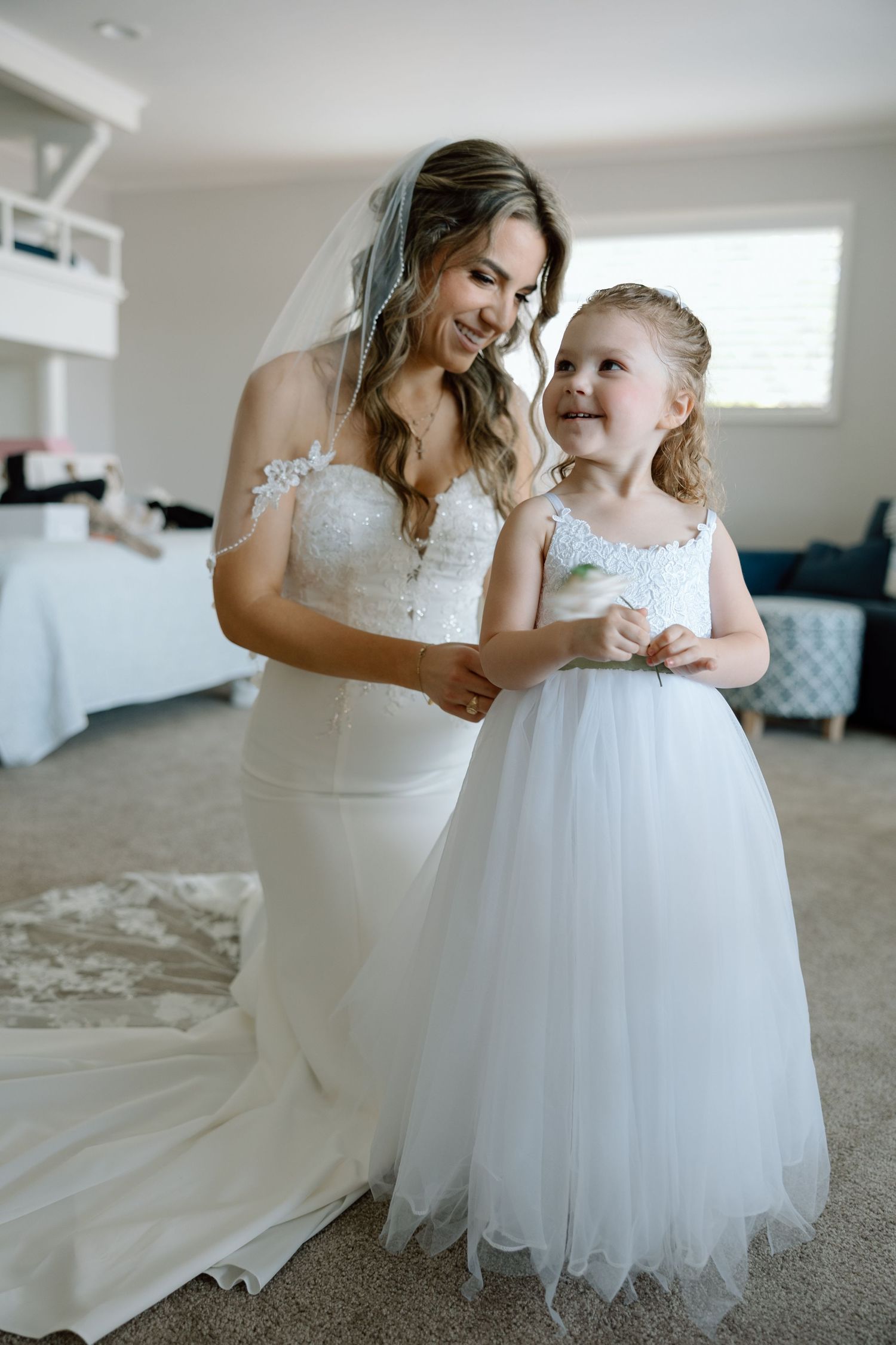 A sweet moment shared between a bride and flower girl in matching white dresses.
