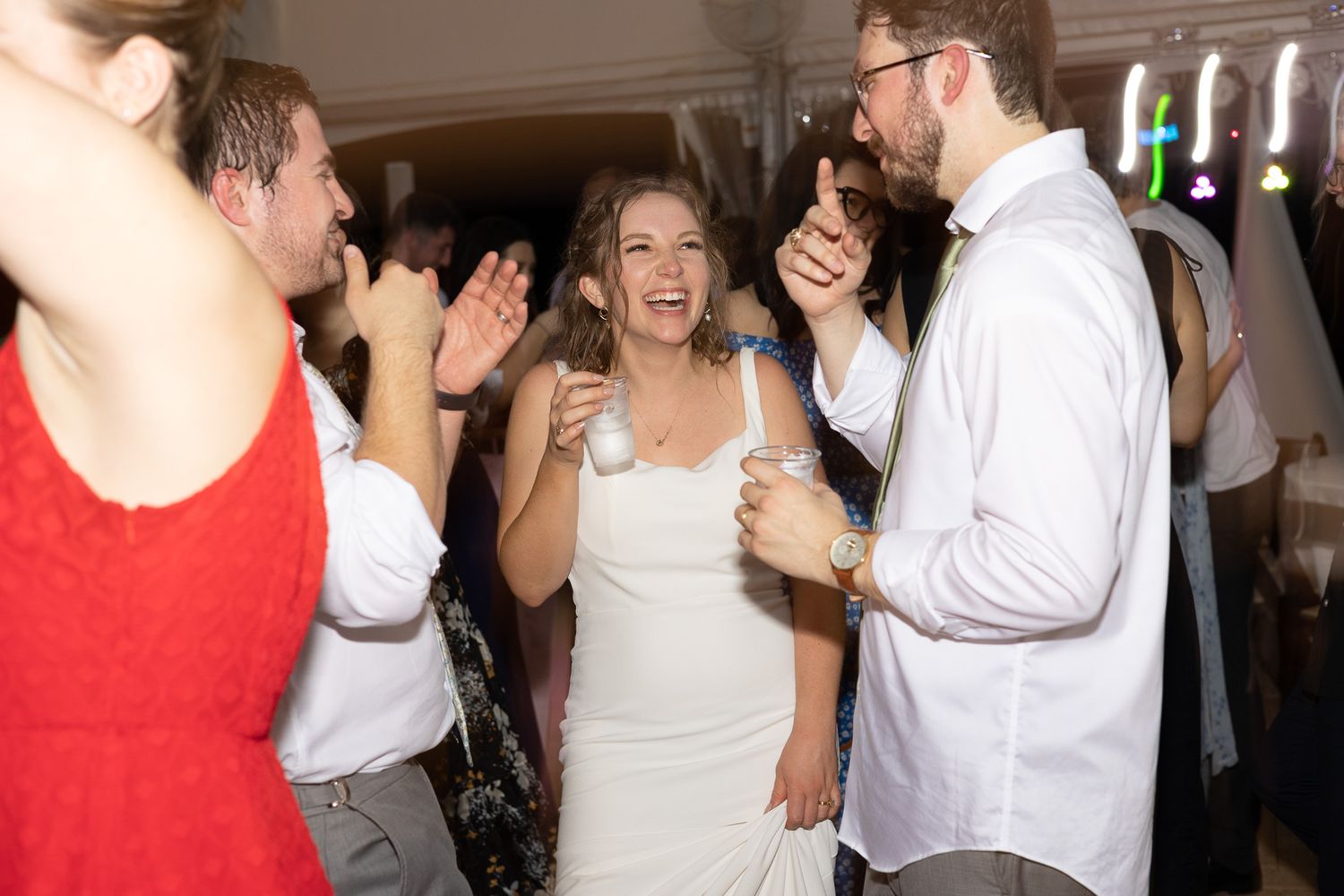 Wedding guests dance and celebrate joyfully at a reception party.