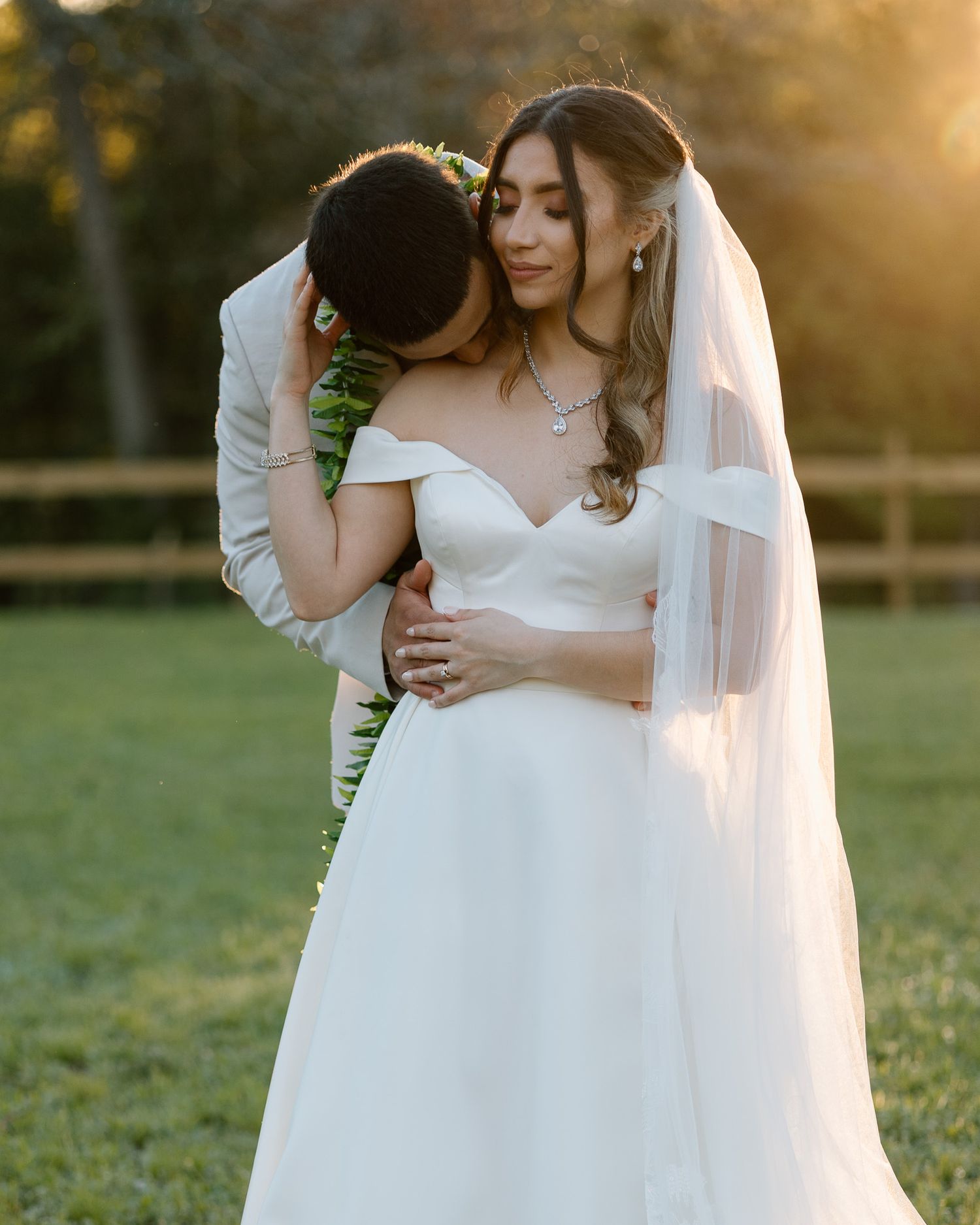 Intimate wedding portrait of couple embracing during golden hour in outdoor garden setting.