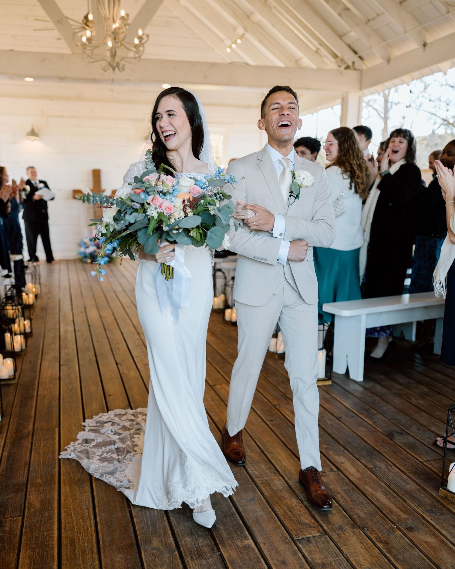Joyful newlyweds walking down aisle with colorful bouquet after wedding ceremony.