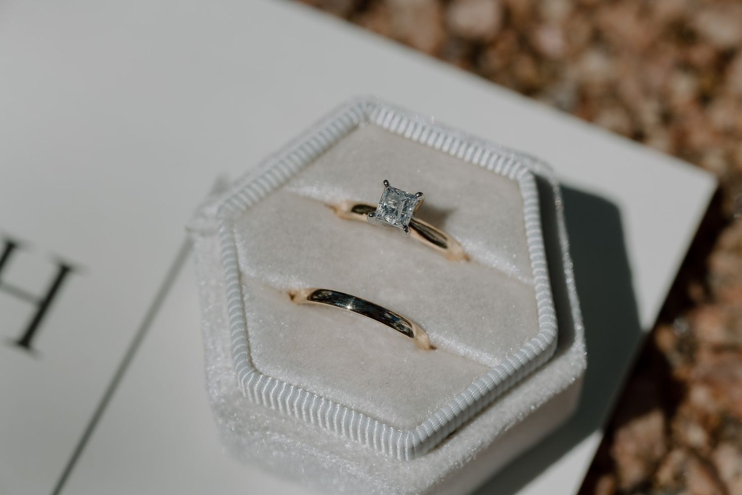 Wedding rings displayed in hexagonal white velvet ring box.