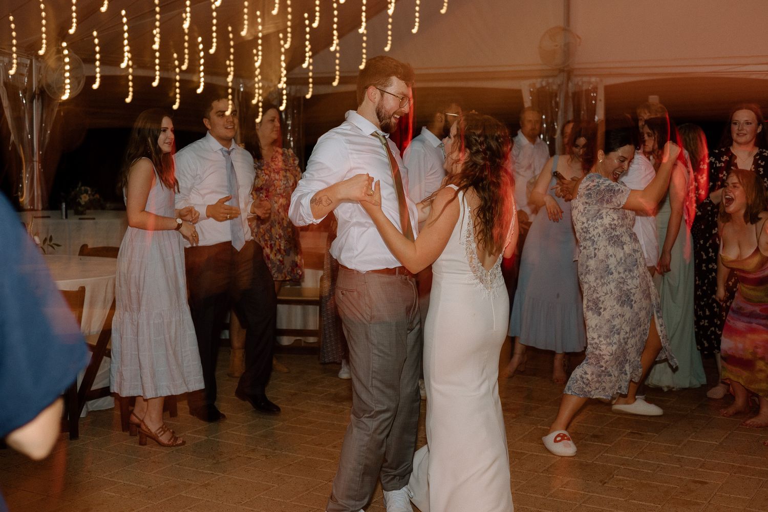 Wedding reception dance party with string lights creating a warm atmosphere.