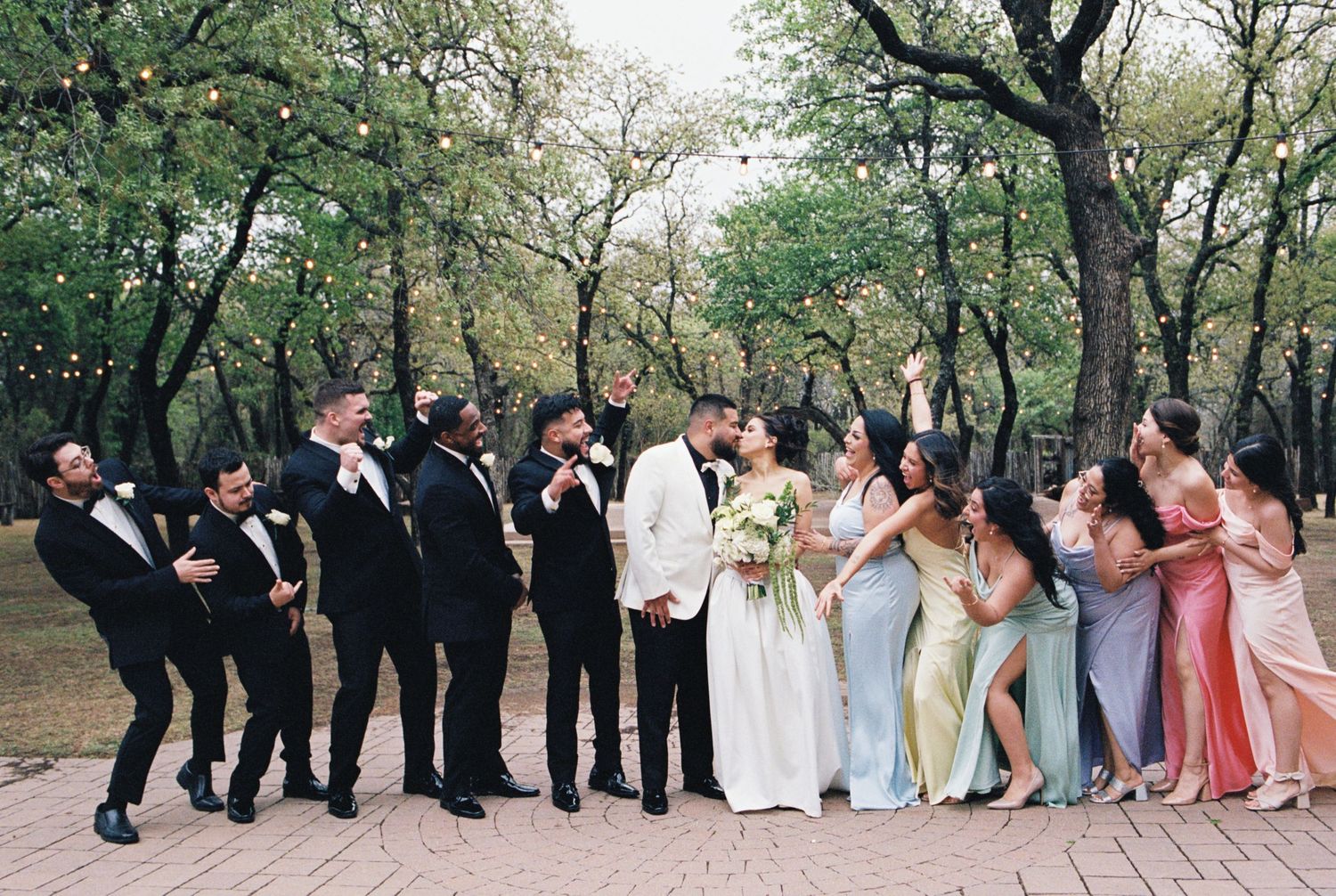 Candid fun photo of wedding party celebrating outdoors in formal attire.