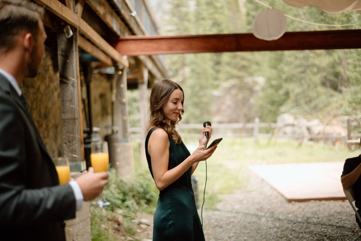 A woman in a dark green dress gives a speech at an outdoor venue.