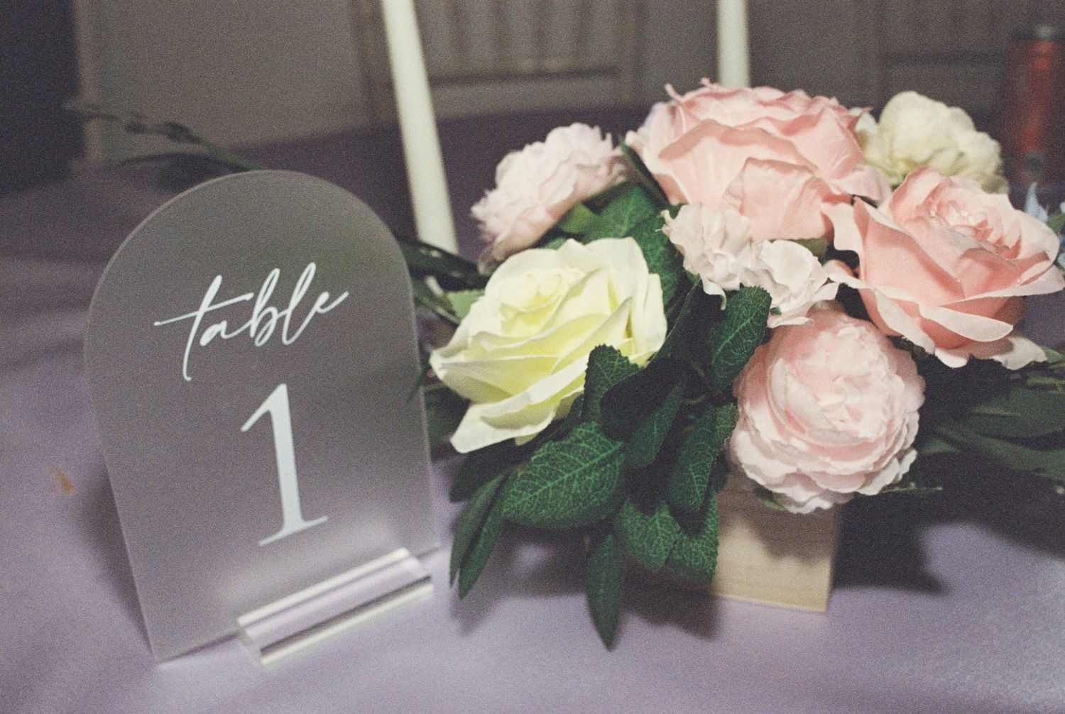 Wedding table number one display with pink and cream roses in a floral centerpiece arrangement.