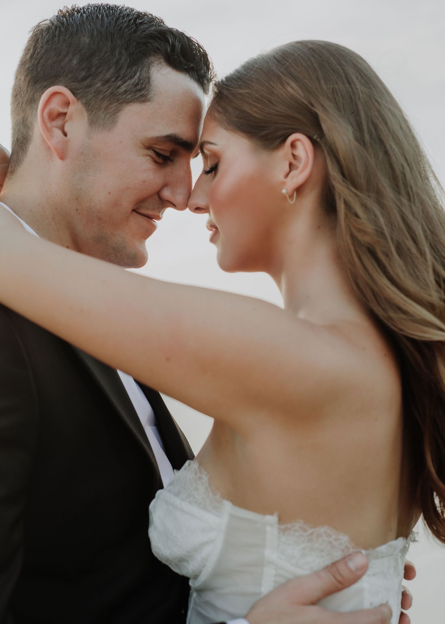 An intimate moment between a couple in formal attire captured in soft lighting.