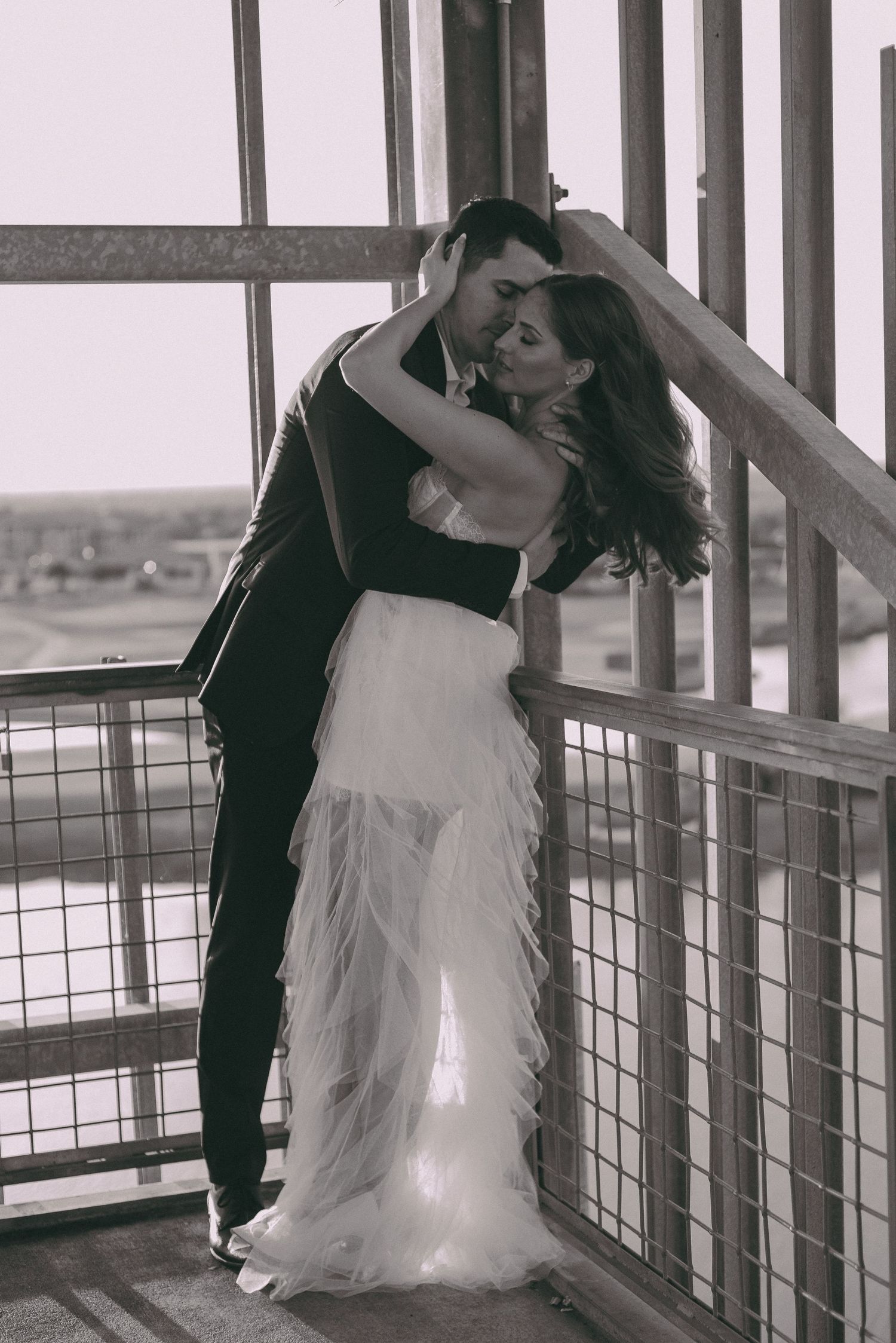 A romantic black and white photo shows a couple dancing intimately on a balcony overlooking a scenic view.