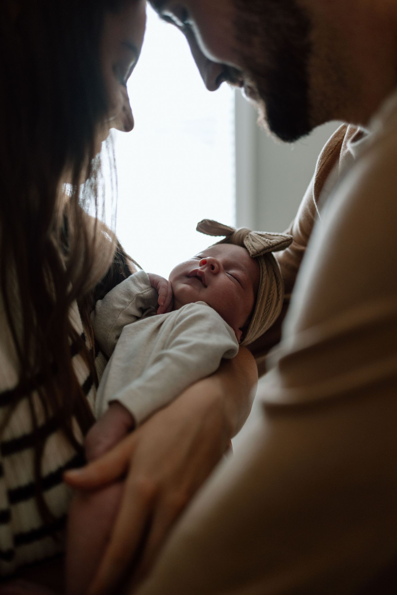 Intimate silhouette portrait of parents gazing at their newborn baby.