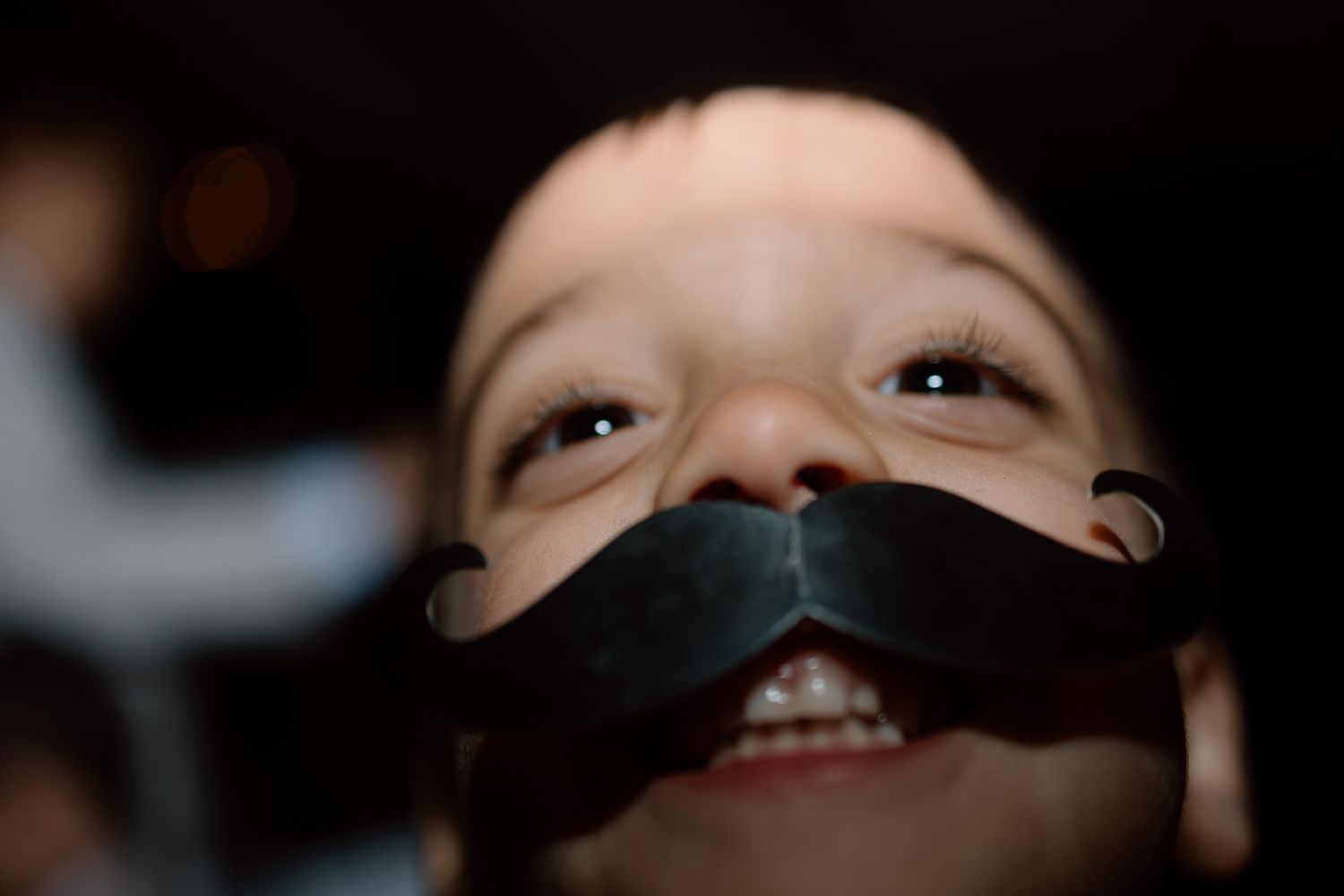 Close up shot of child wearing playful fake mustache decoration.