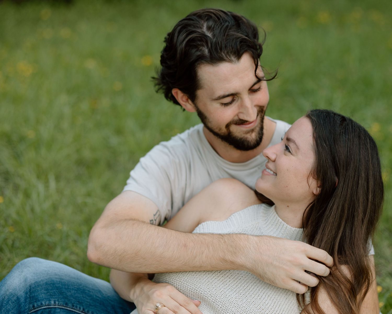 Loving outdoor maternity portrait on grass with couple in casual wear.