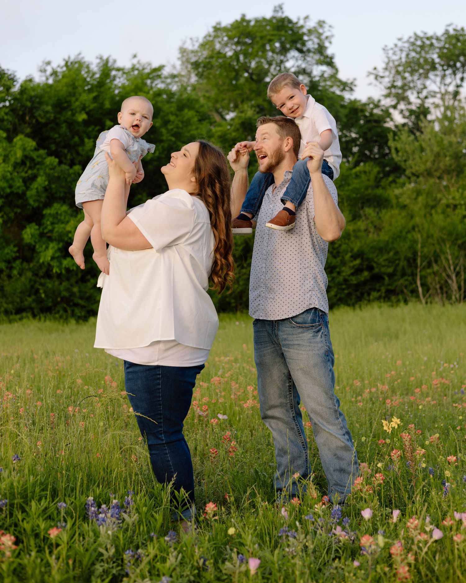 Family enjoying a playful moment together in a wildflower meadow on a sunny day.