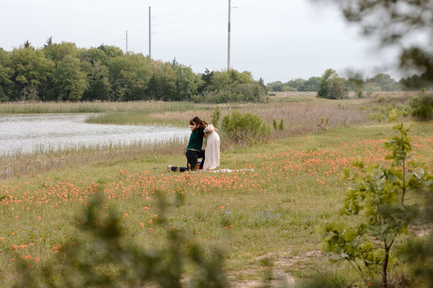 Two figures in a serene moment among orange wildflowers with a lake view documentary photography college station Texas.