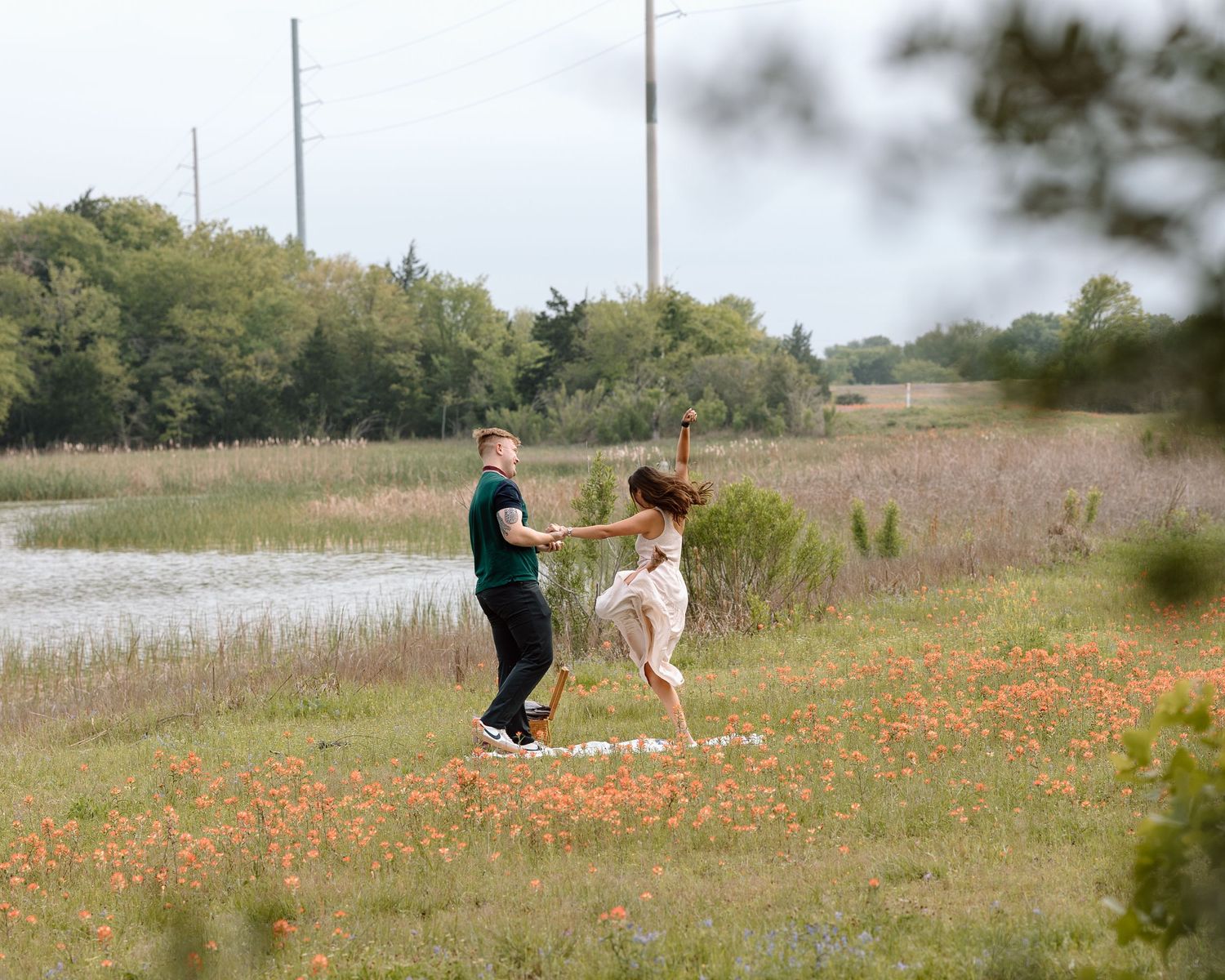 A joyful dance in a field of orange wildflowers near the water's edge.