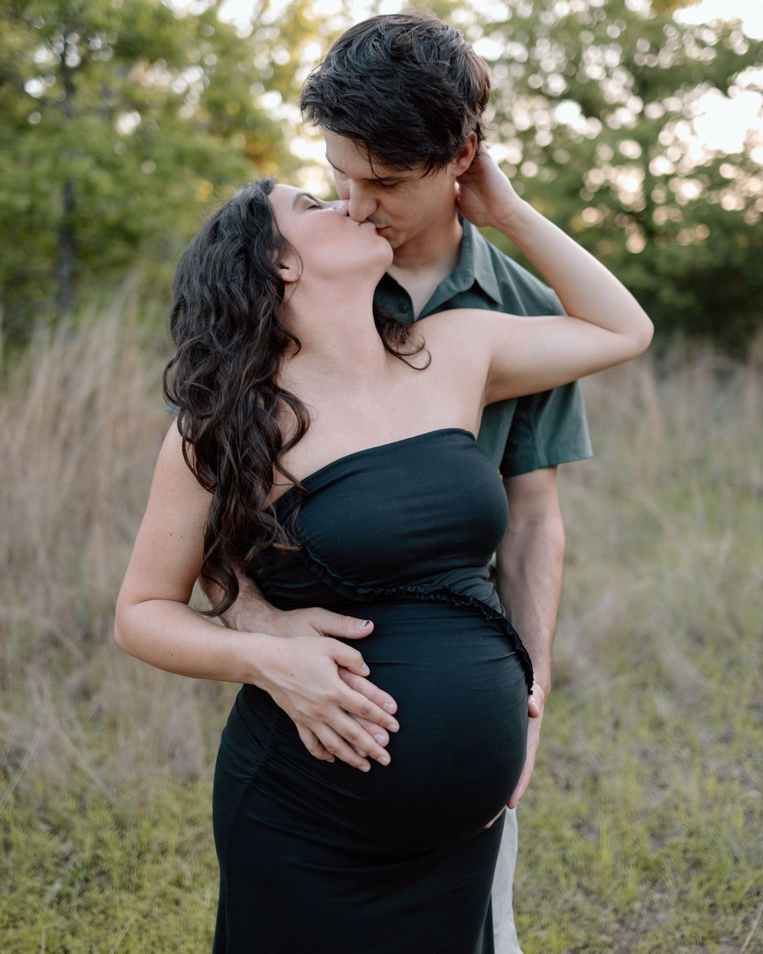 Romantic maternity photoshoot featuring couple in loving embrace amidst natural scenery.