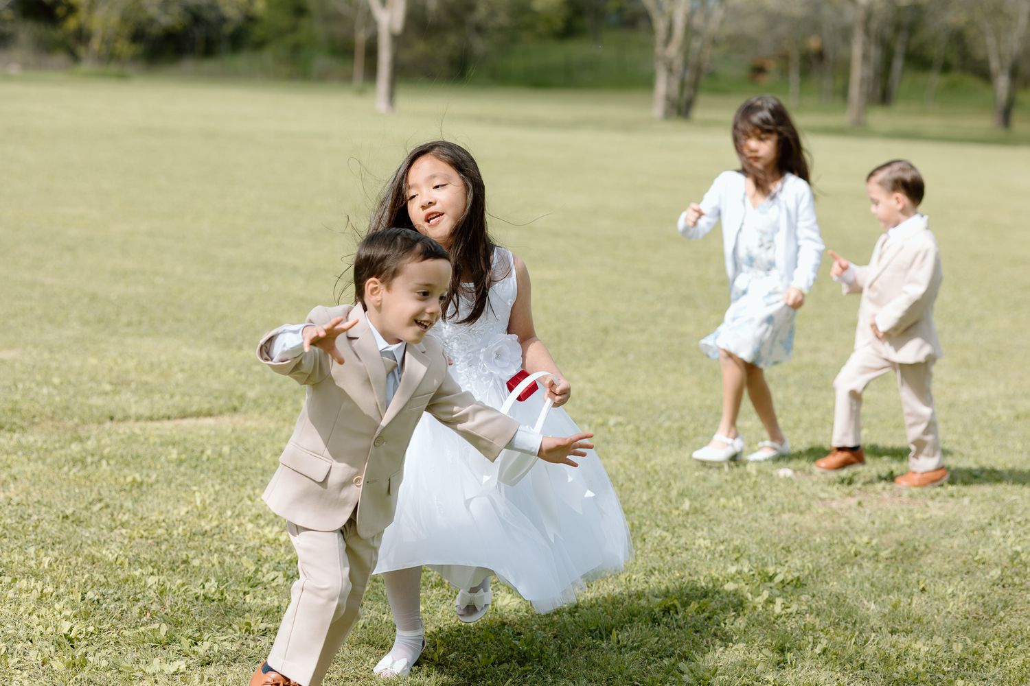 Children playing and running on grass during a wedding celebration.