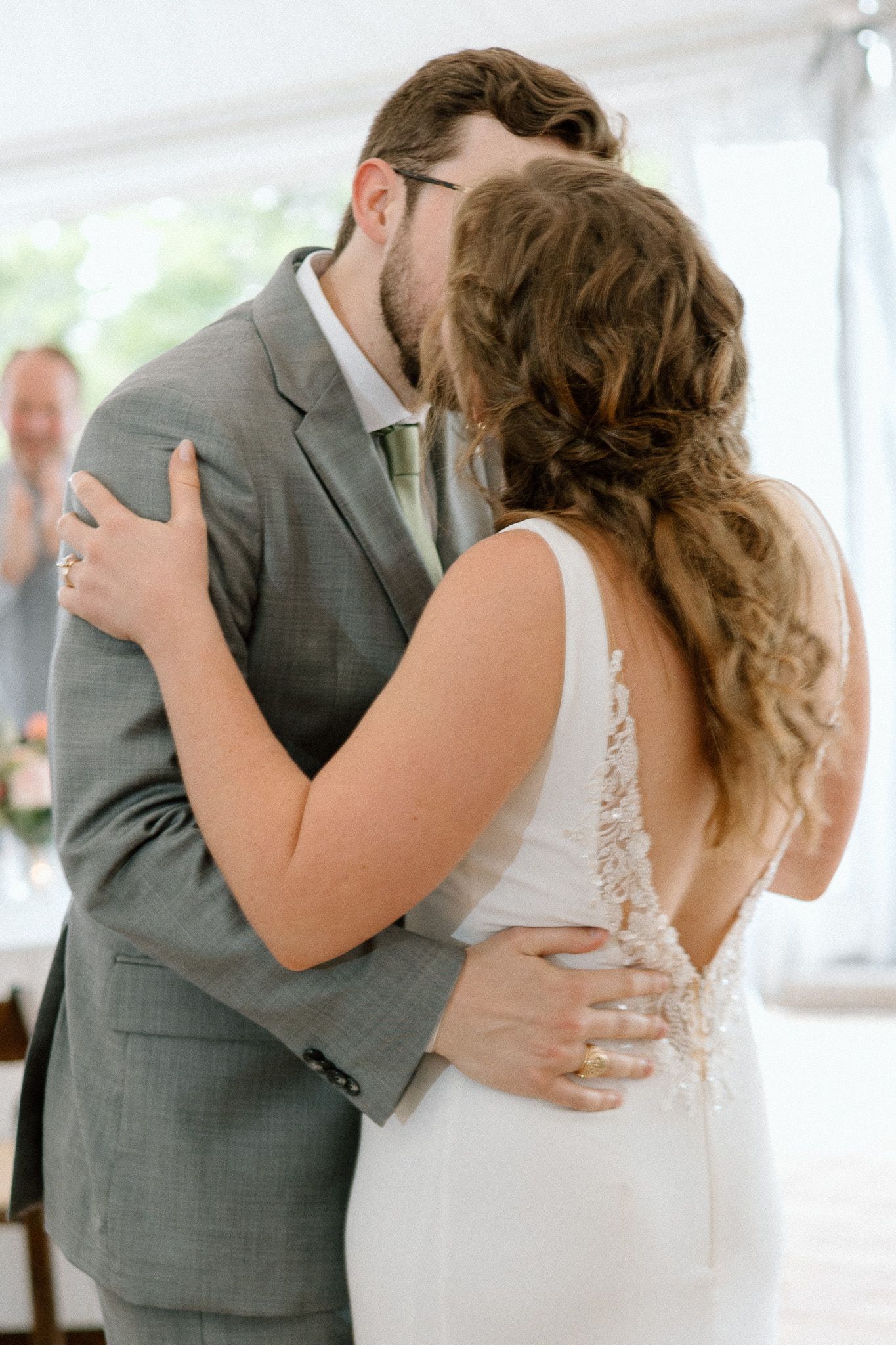 Romantic first dance moment between newlyweds in an elegant white tent reception venue.