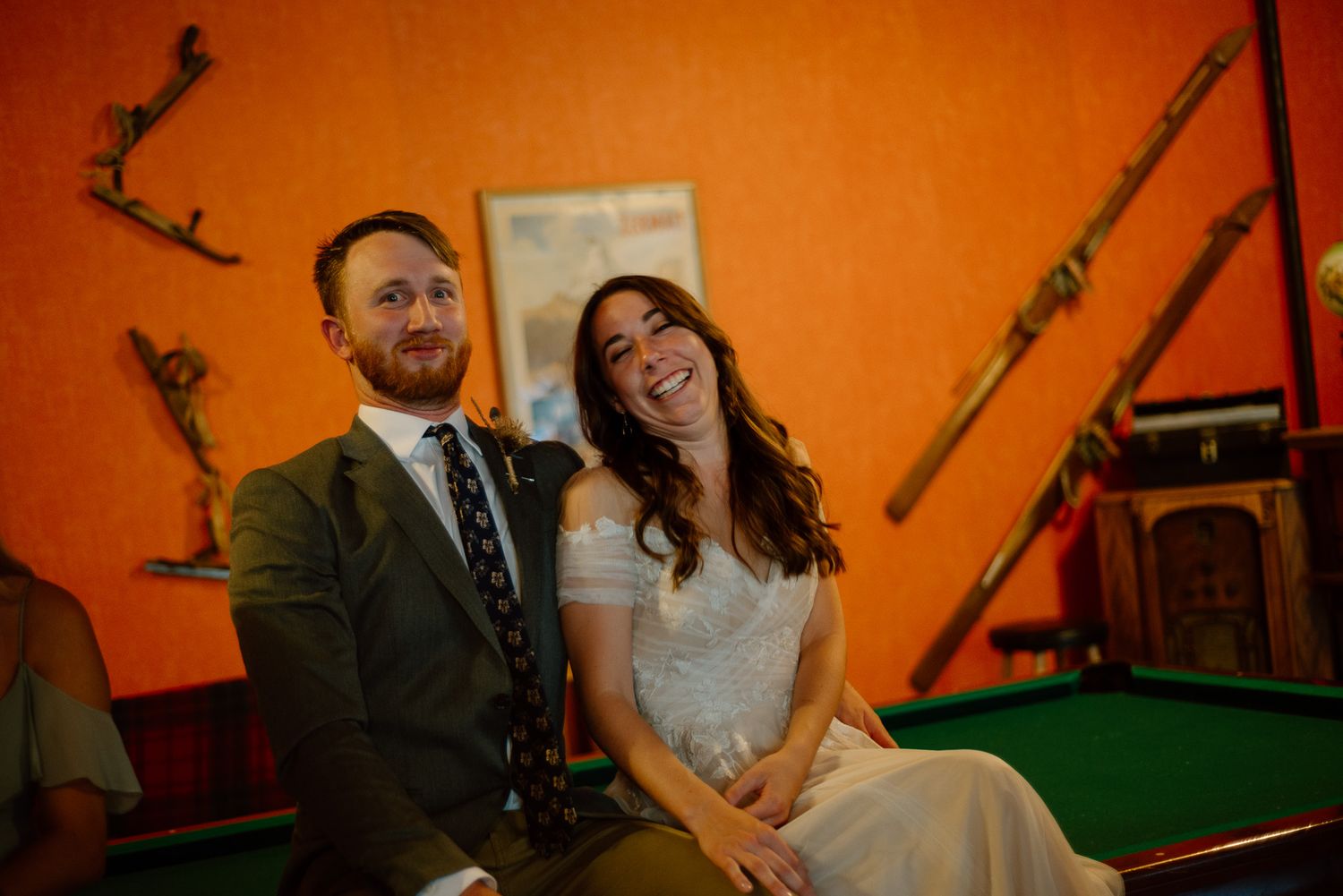 A couple shares a joyful moment in a room with orange walls and antique decor.