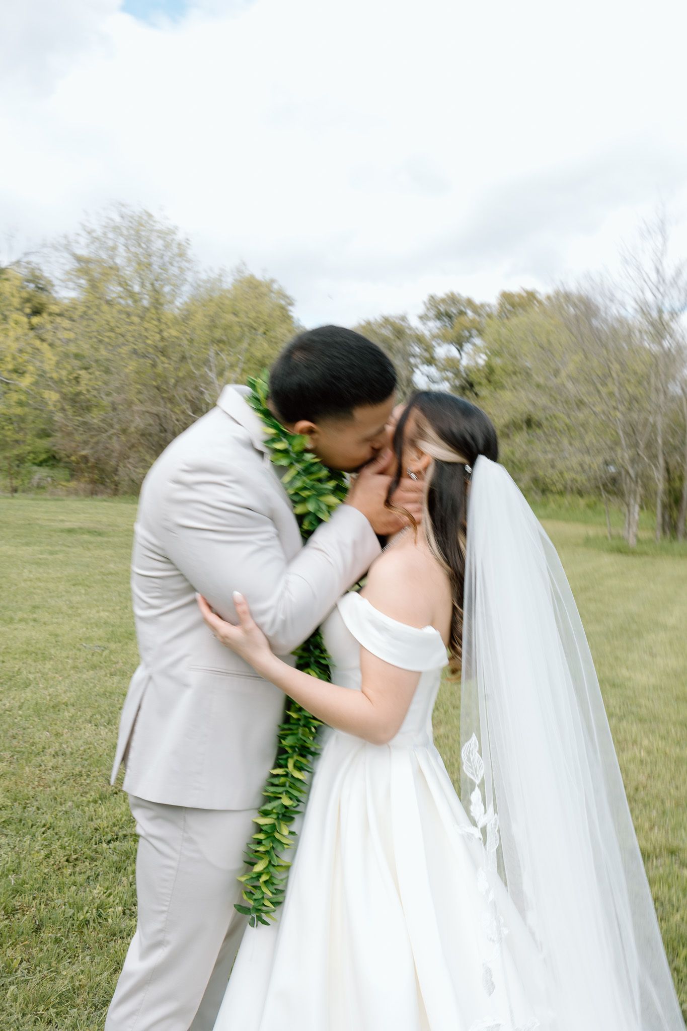 A tender moment between newlyweds wearing traditional wedding attire outdoors.
