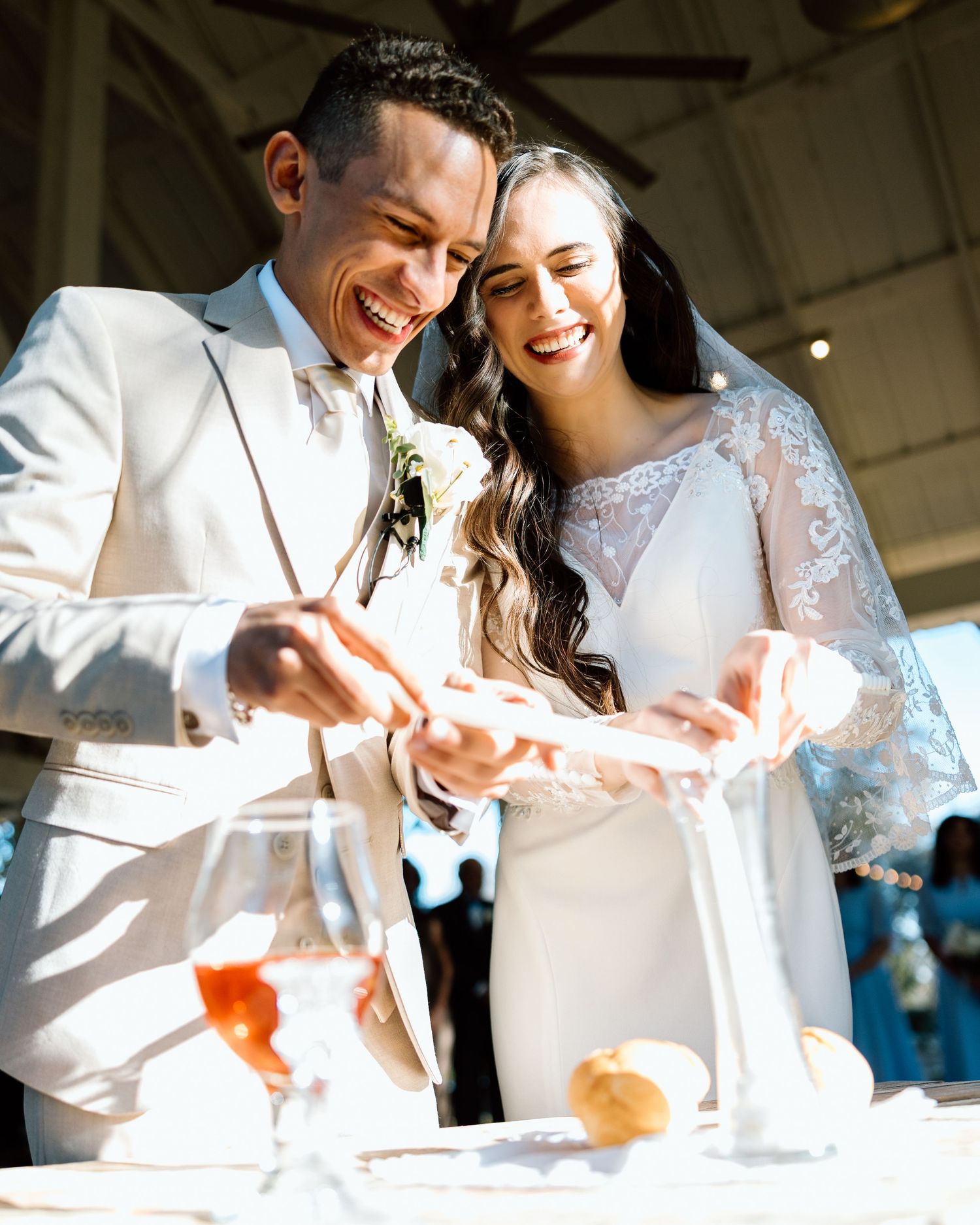Smiling bride and groom cutting wedding cake together at elegant reception ceremony.