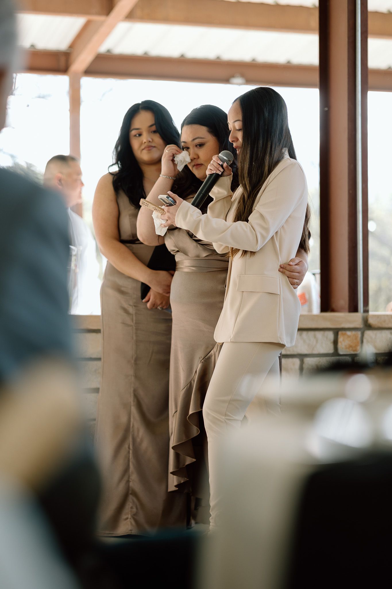 Wedding guests in neutral tones share an intimate moment during reception.