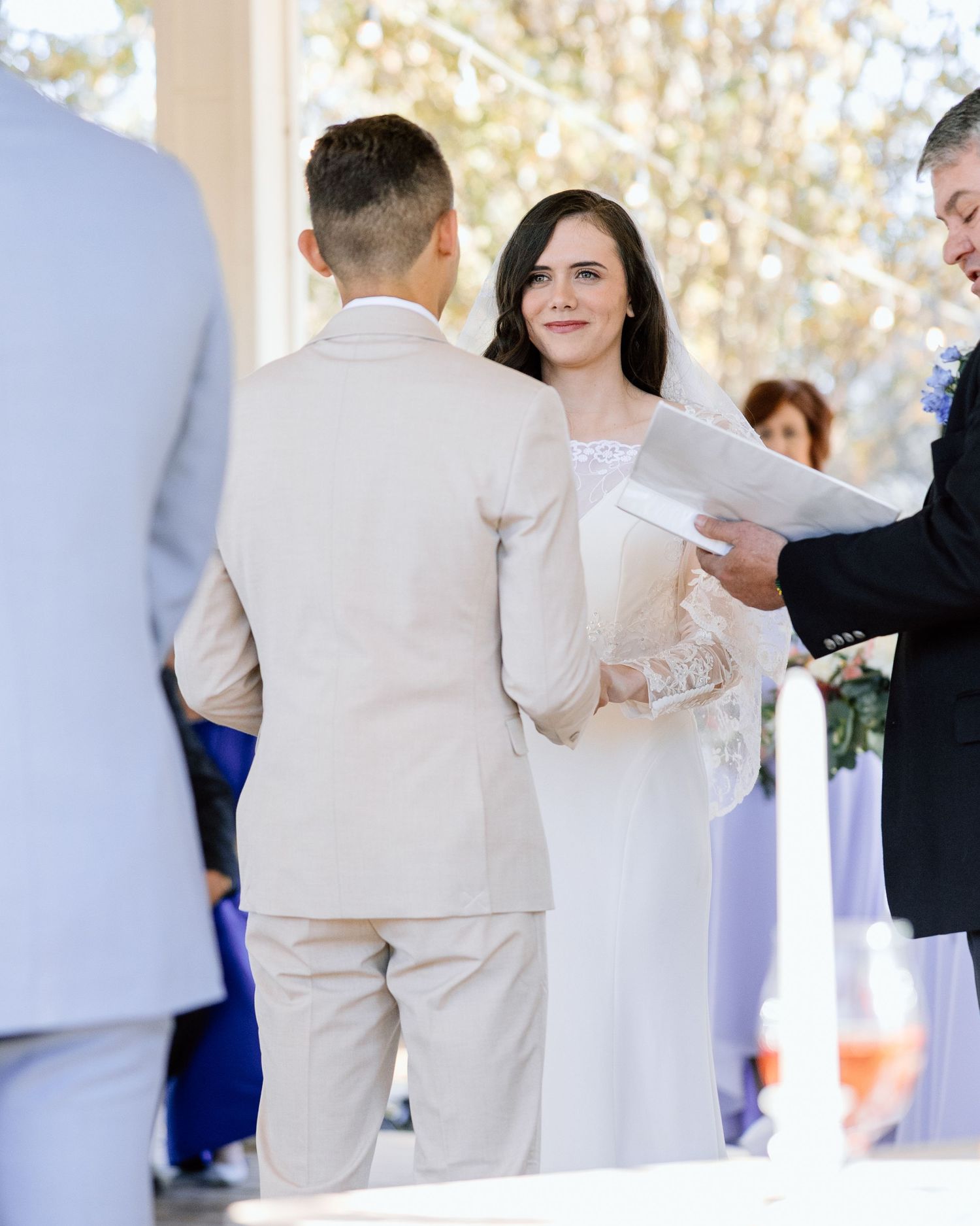 Bride and groom exchanging vows at outdoor wedding ceremony with officiant.