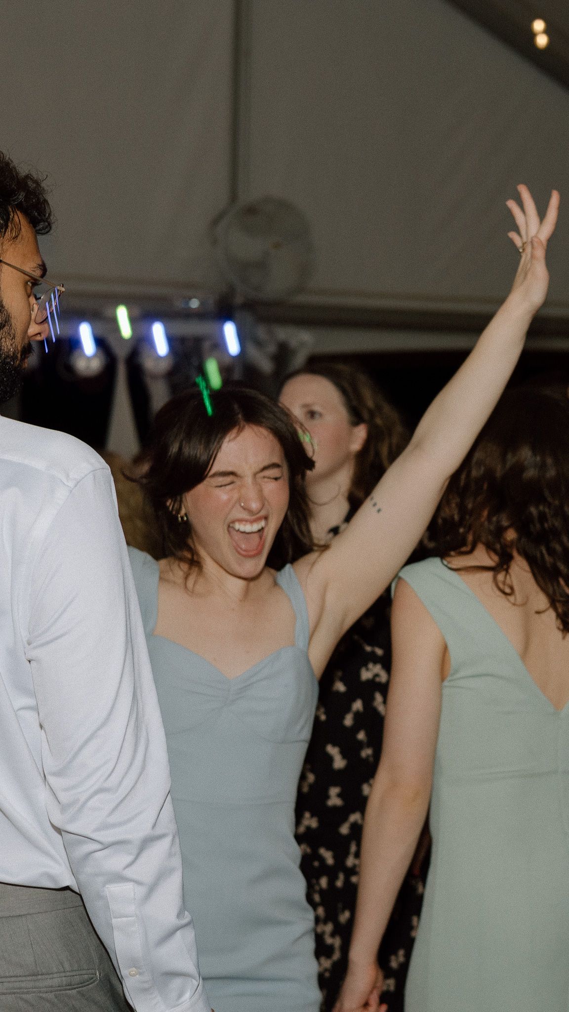 Bridesmaid in light blue dress dancing enthusiastically at wedding reception.
