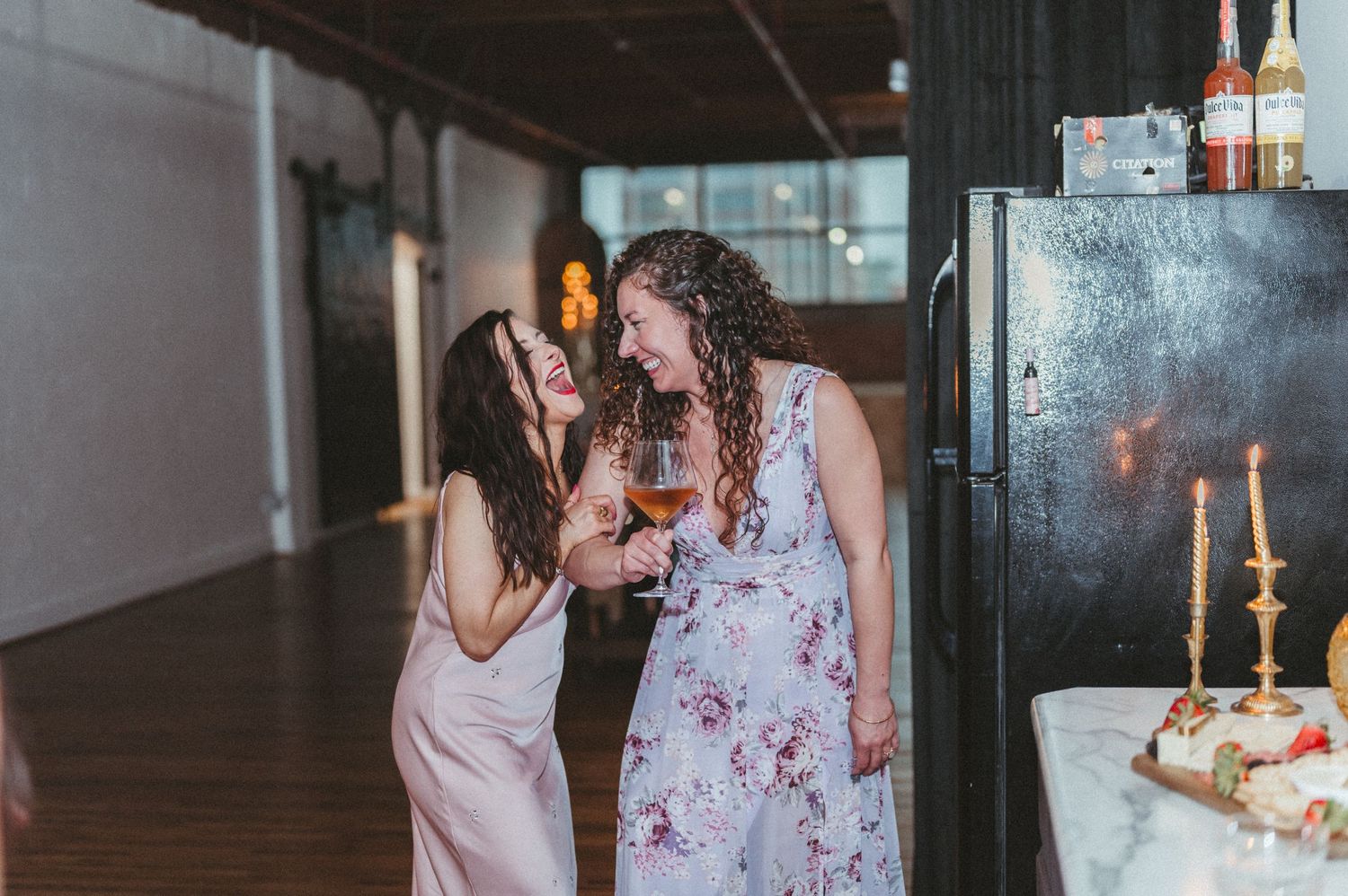 Two people chatting and laughing in a sunlit industrial event space.