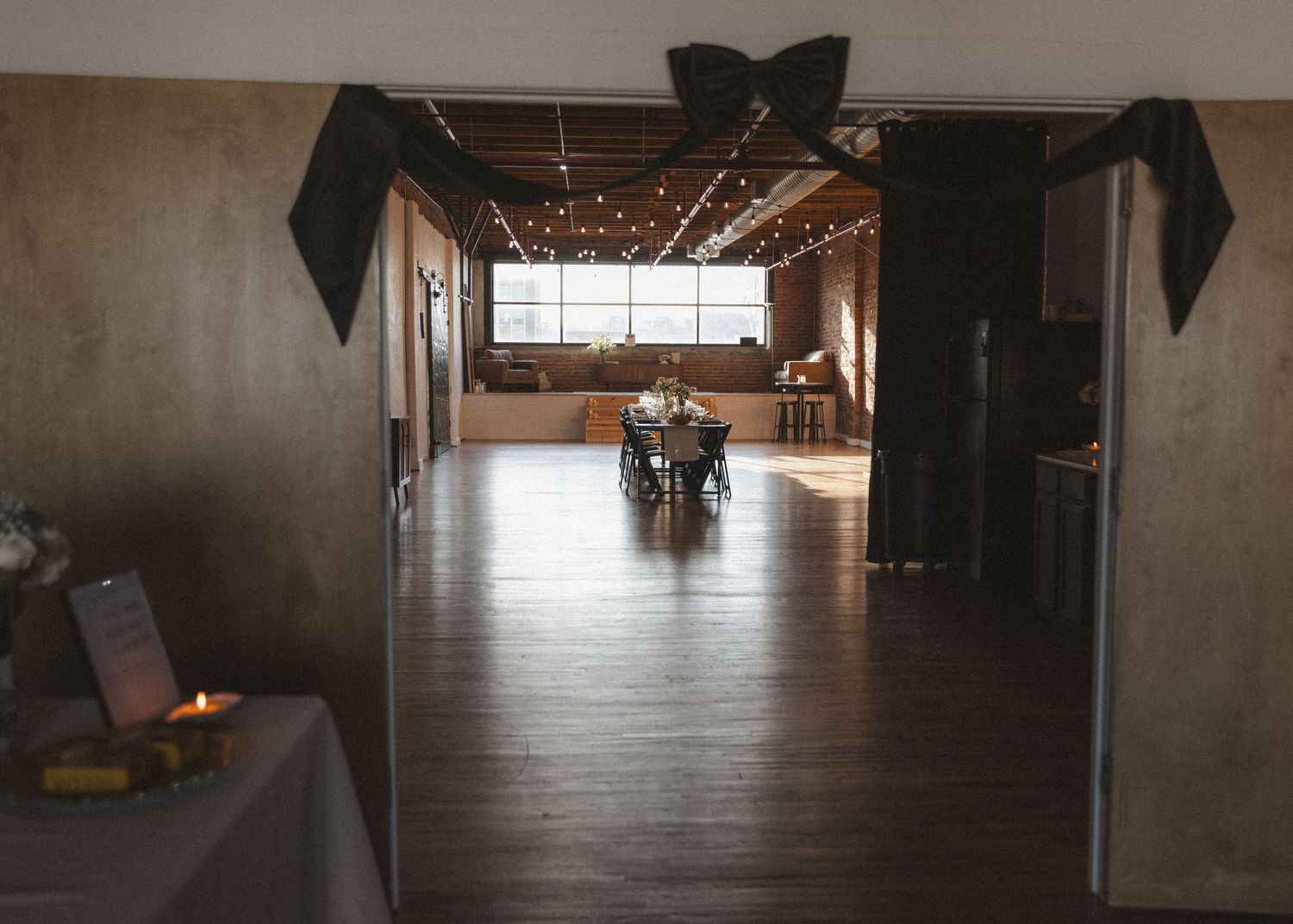 Empty industrial wedding venue with hardwood floors and exposed brick walls.