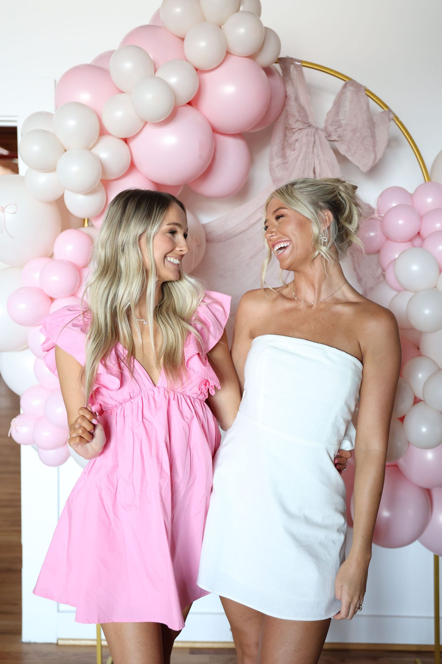Festive pink and white balloon display with elegant party outfits.