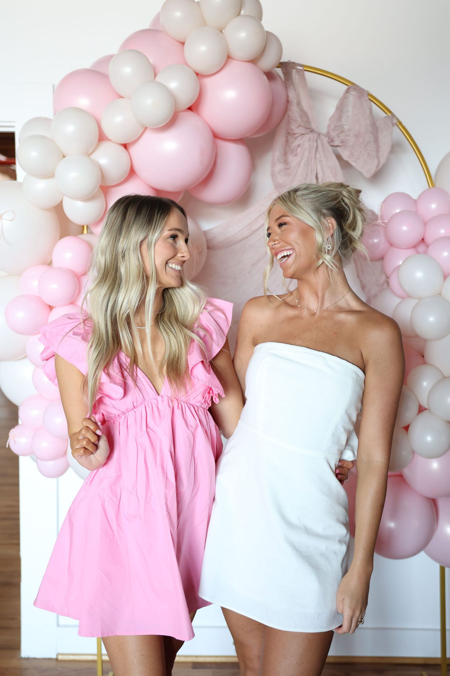Pink and white balloon arch installation with gold circular frame for wedding photo opportunities.