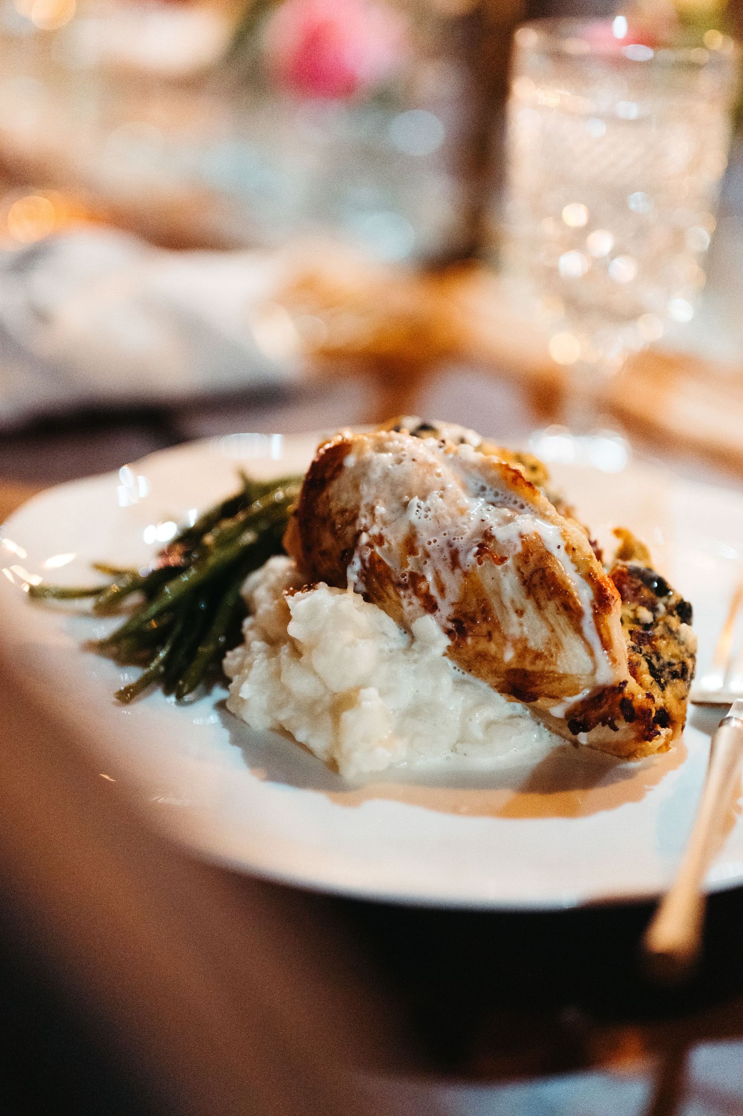 Gourmet dinner plate with chicken, mashed potatoes and asparagus in elegant restaurant setting.