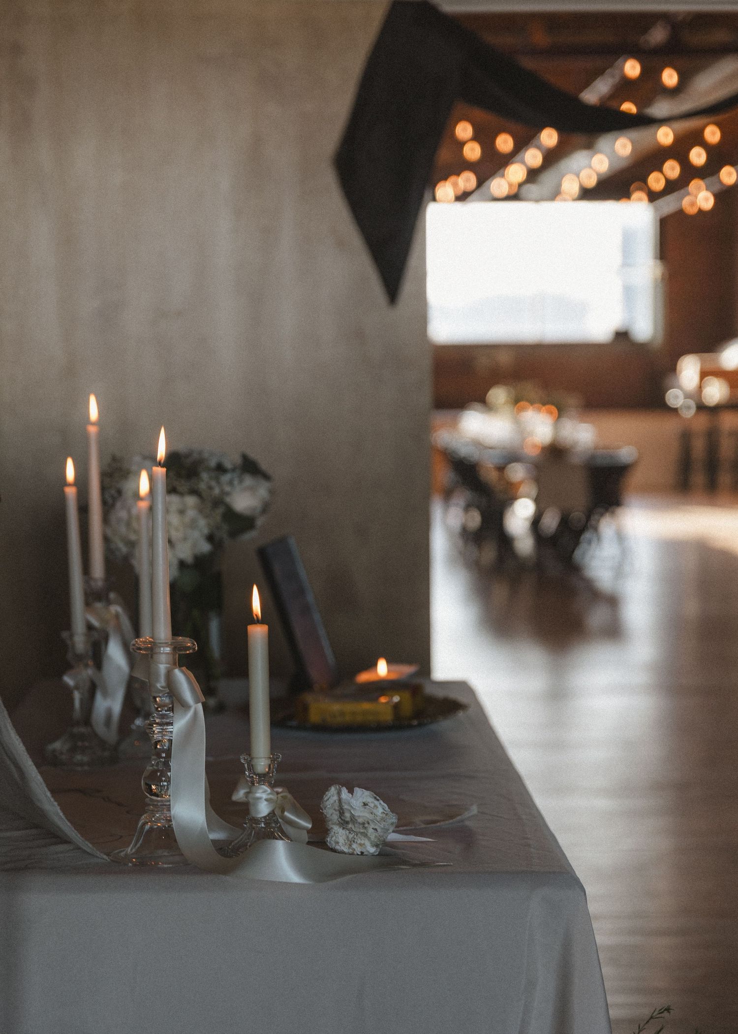 Moody table setting with white taper candles and romantic ambient lighting.