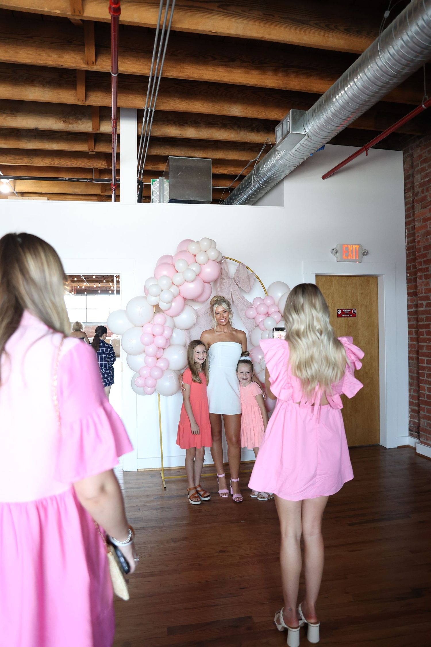 Event space decorated with pink and white balloon arch against brick wall.