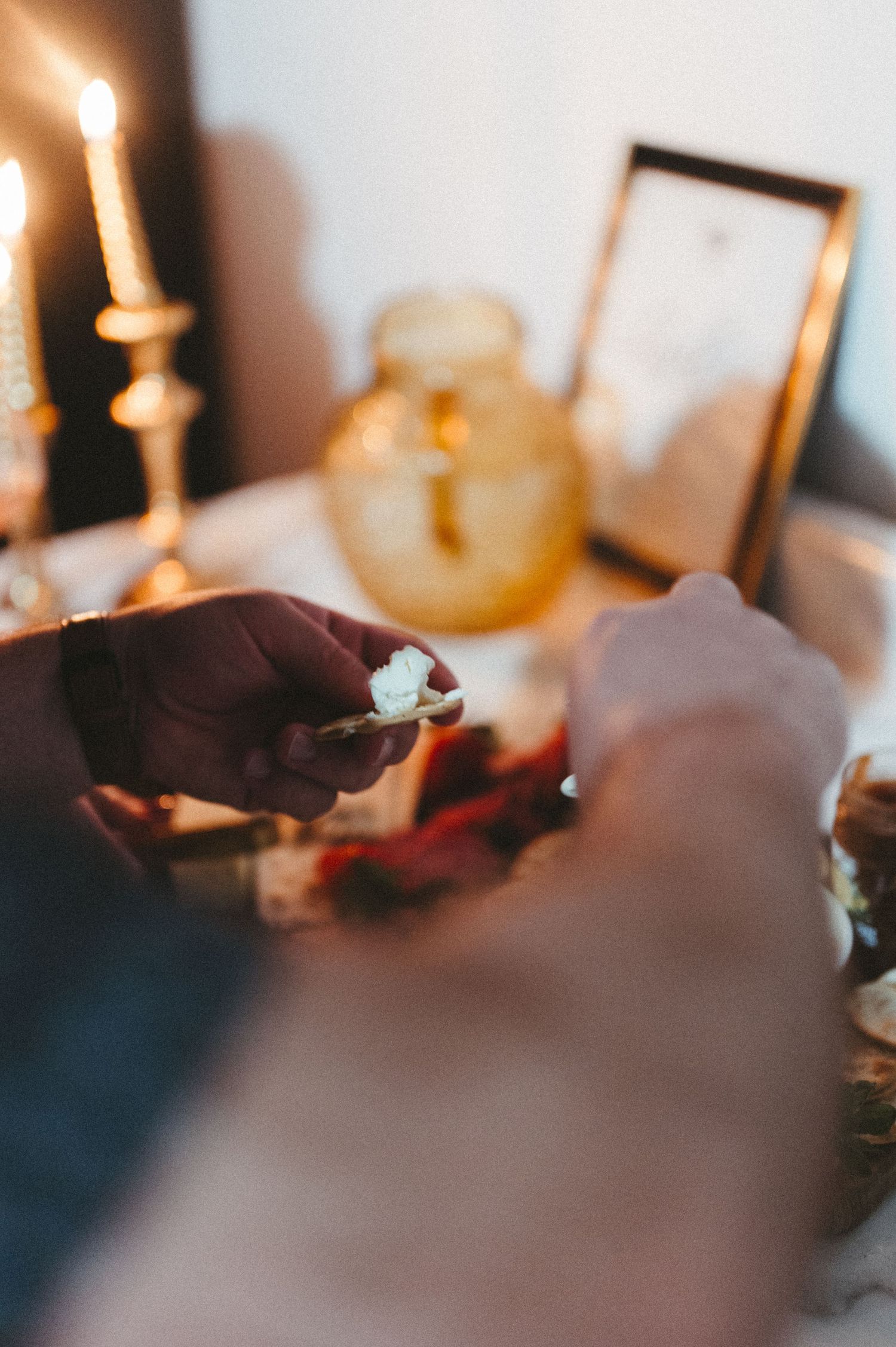 Hands preparing appetizers on a candlelit table with decorative elements.