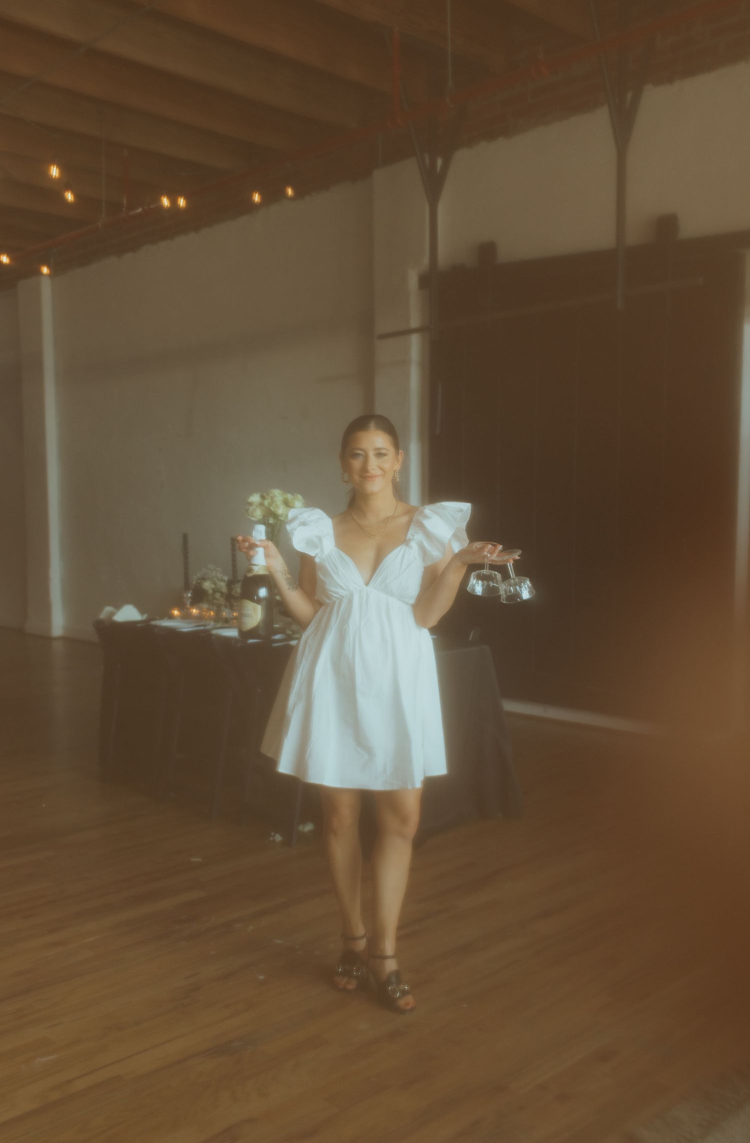 Person in white mini dress posing in industrial event space.