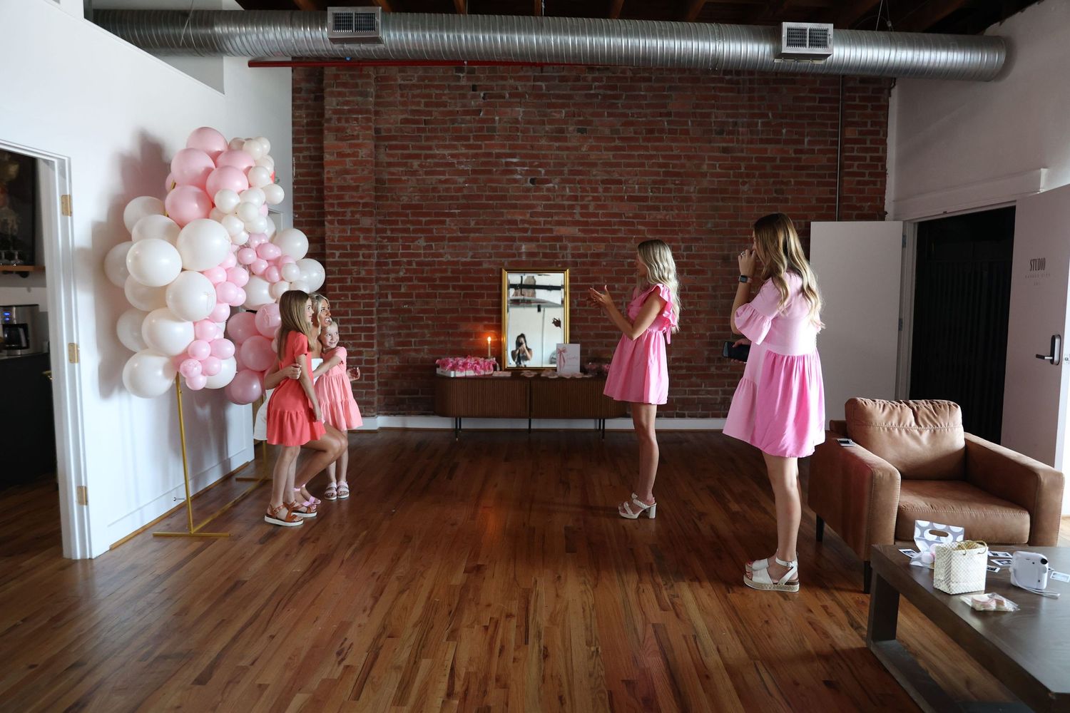 Pink and white balloon arch decorates an industrial-style event space.