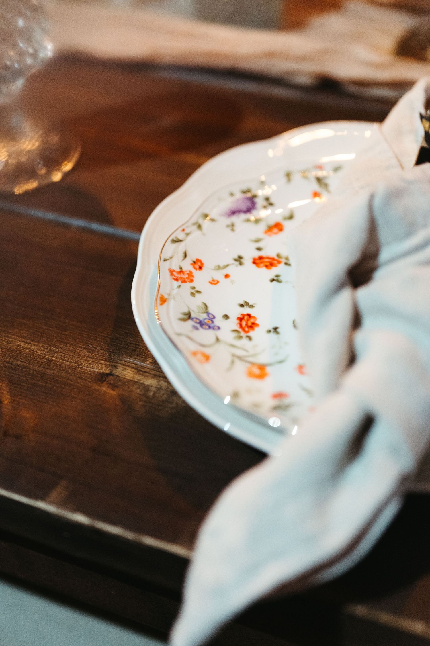 Vintage floral plate with delicate orange and purple flower pattern on wooden table.