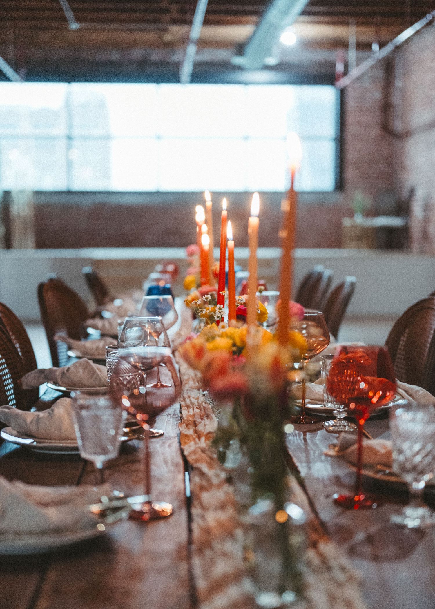Elegant table setting with lit candles and place settings in an industrial space.