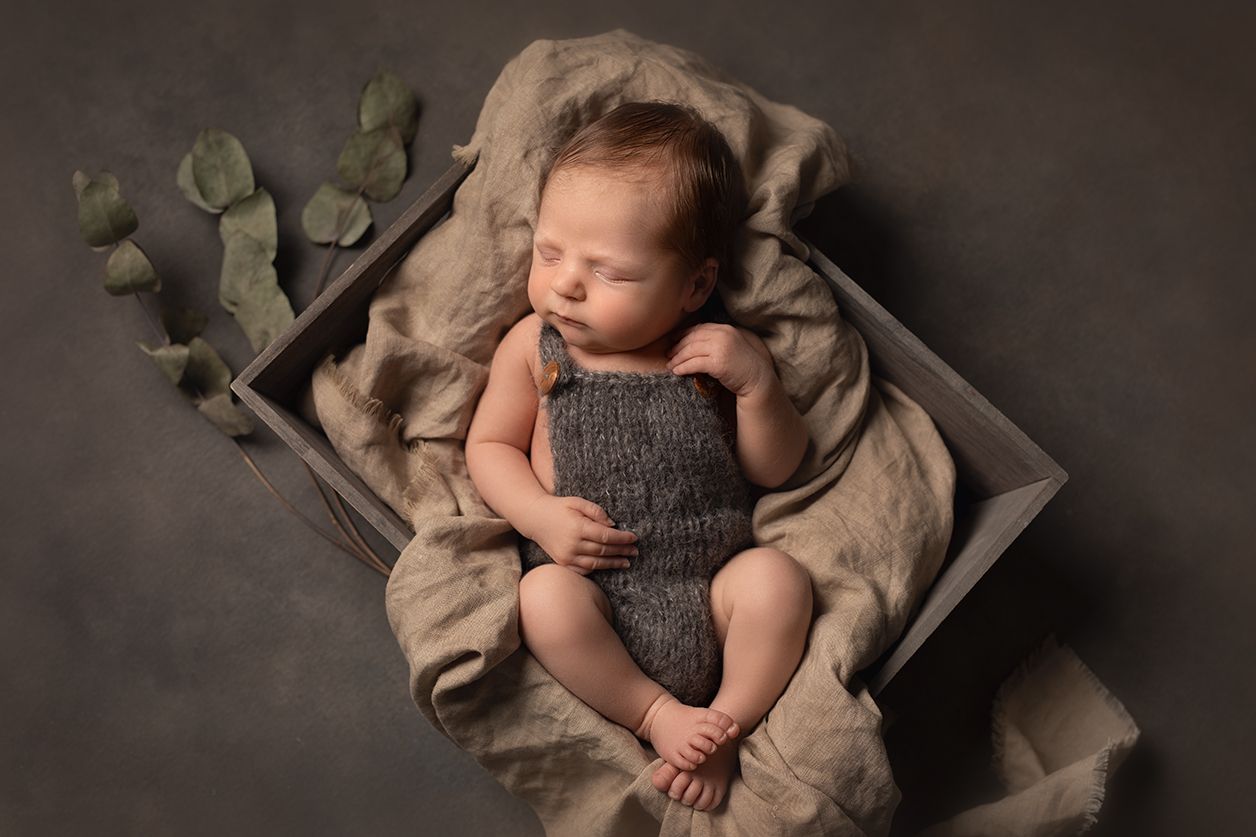 Newbornkuvaus Tuusulassa tummaa taustaa ja rekvisiittaa tunnelmaa luomassa.