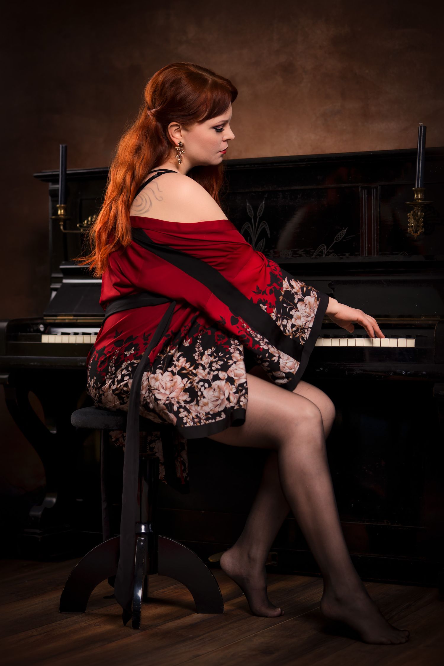 Muotokuva pianoa soittavasta punatukkaisesta naisesta satiinisessa aamutakissa.