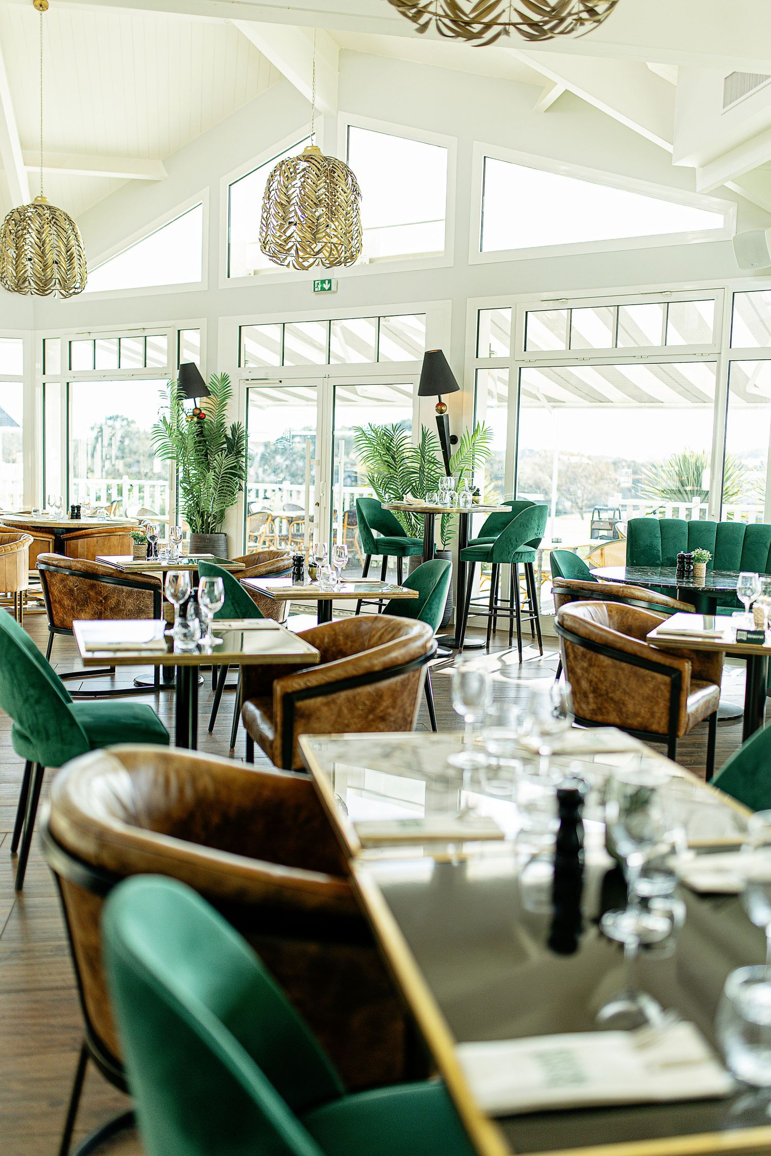 Photo d’un restaurant élégant, tables dressées avec décor raffiné et ambiance chaleureuse sous une lumière tamisée.