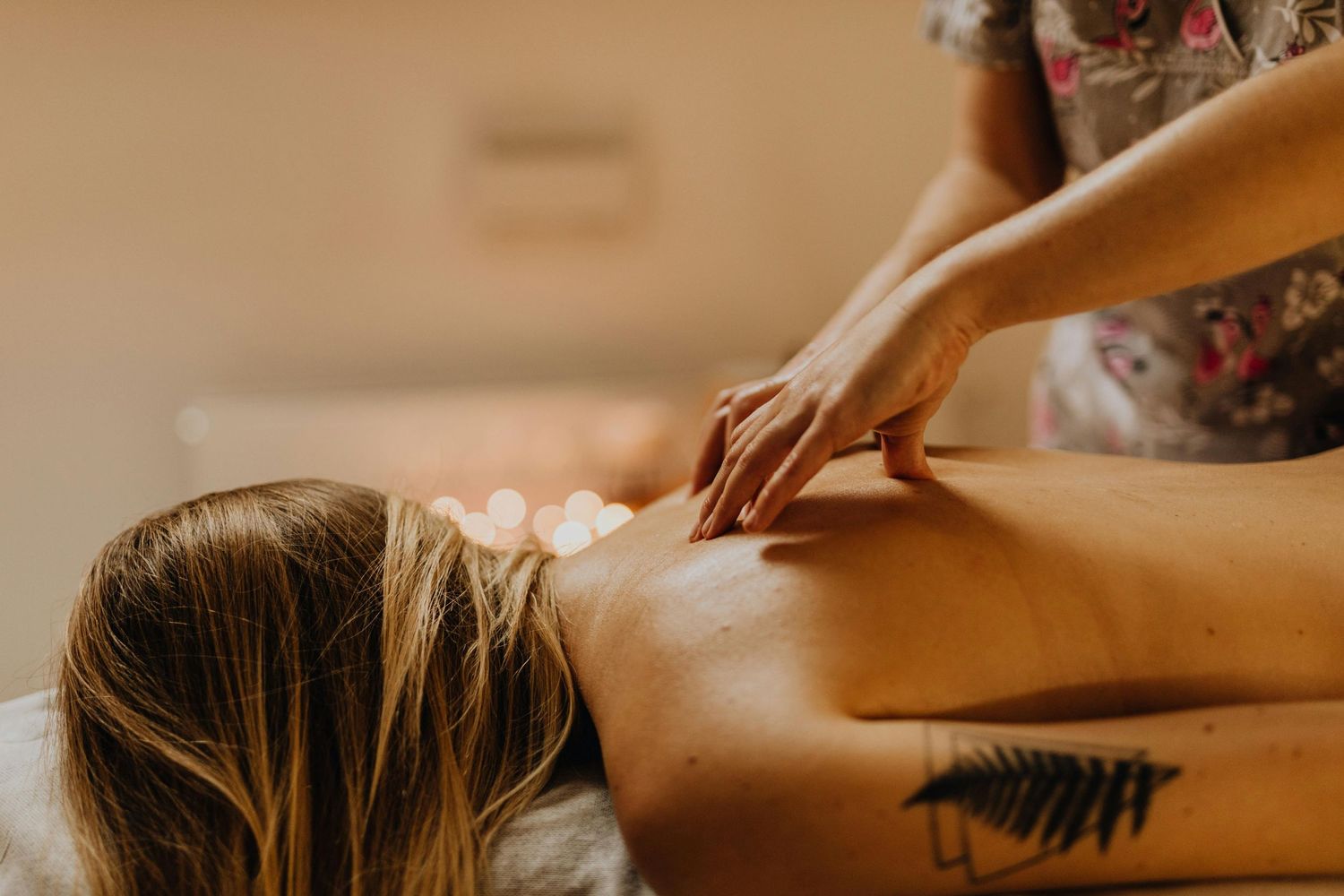 Photo dans un spa, masseuse en action réalisant un massage relaxant, ambiance calme et apaisante avec lumière tamisée.