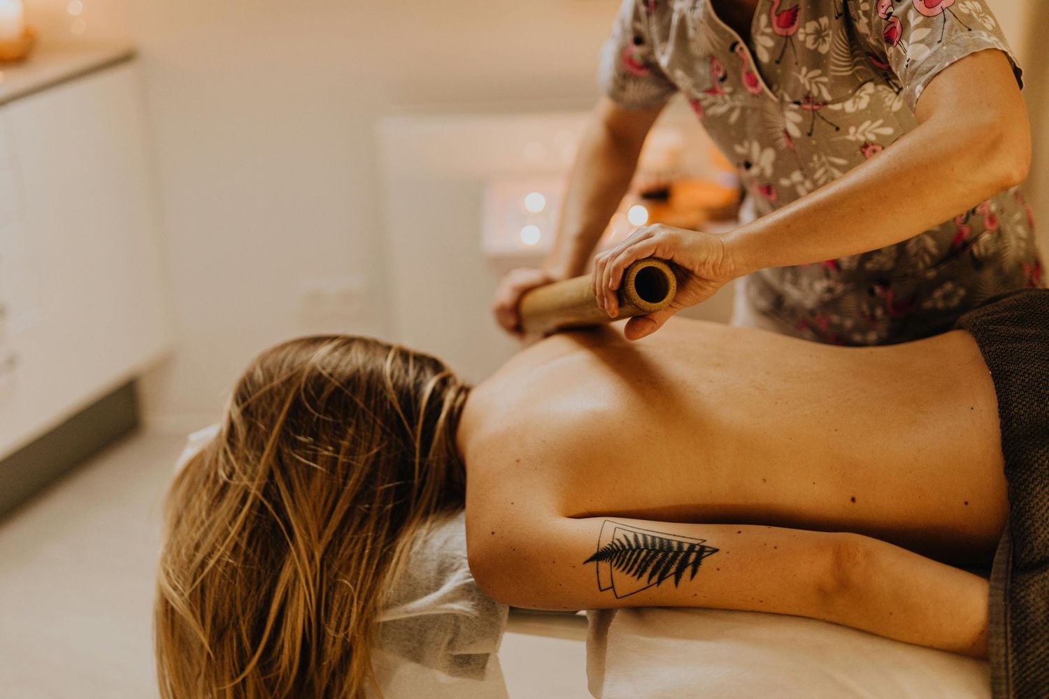Photo dans un spa, masseuse en action réalisant un massage relaxant, ambiance calme et apaisante avec lumière tamisée.