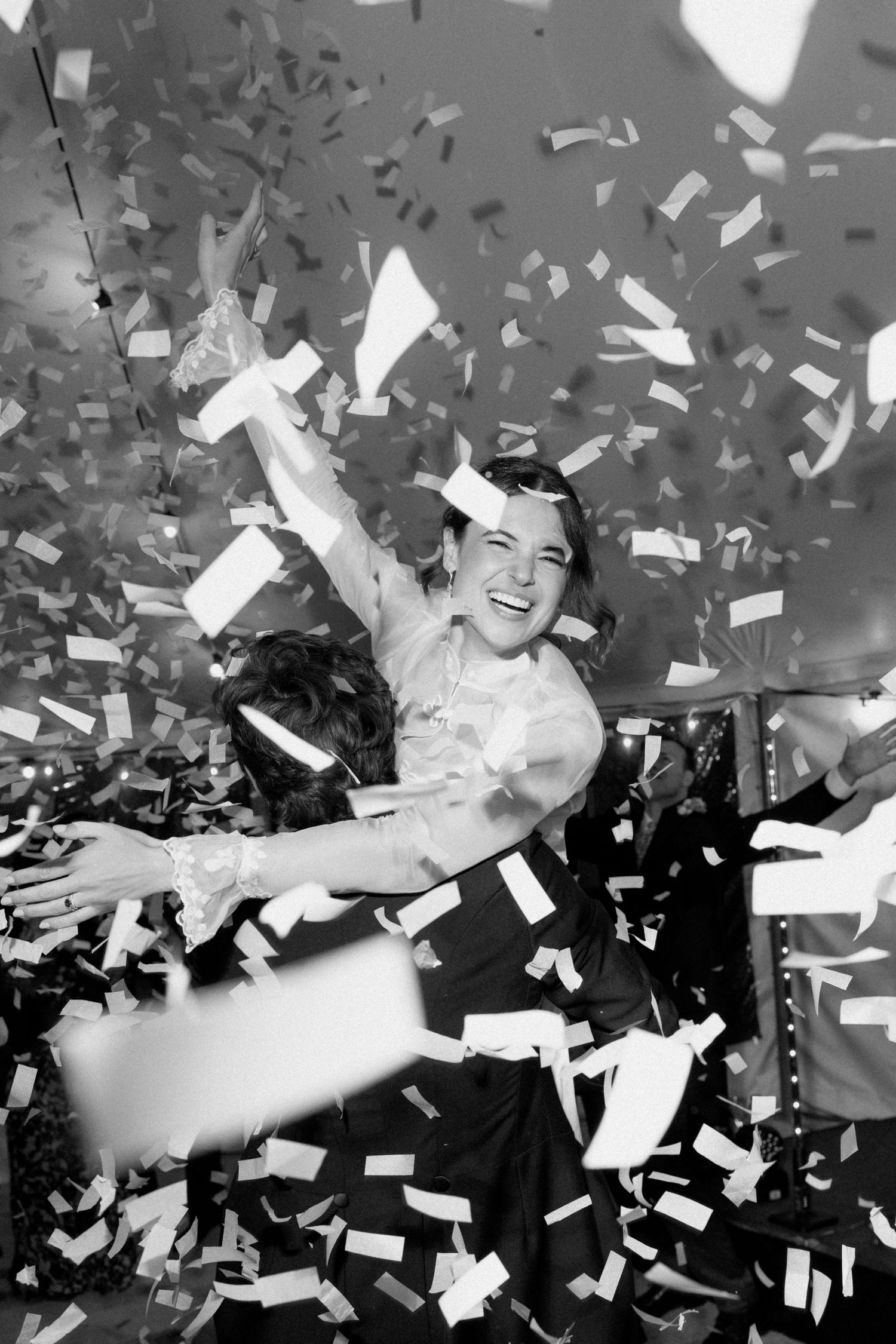 Black and white photo of a joyful person celebrating amid a shower of confetti at a festive party event.